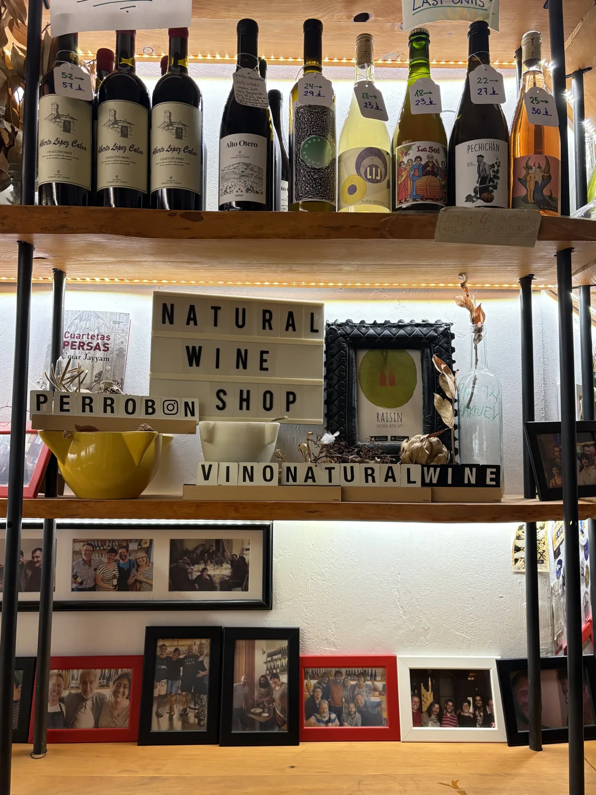 Shelves of natural wine bottles with hand-written price tags below a Natural Wine Shop sign inside La Casa del Perro, Málaga