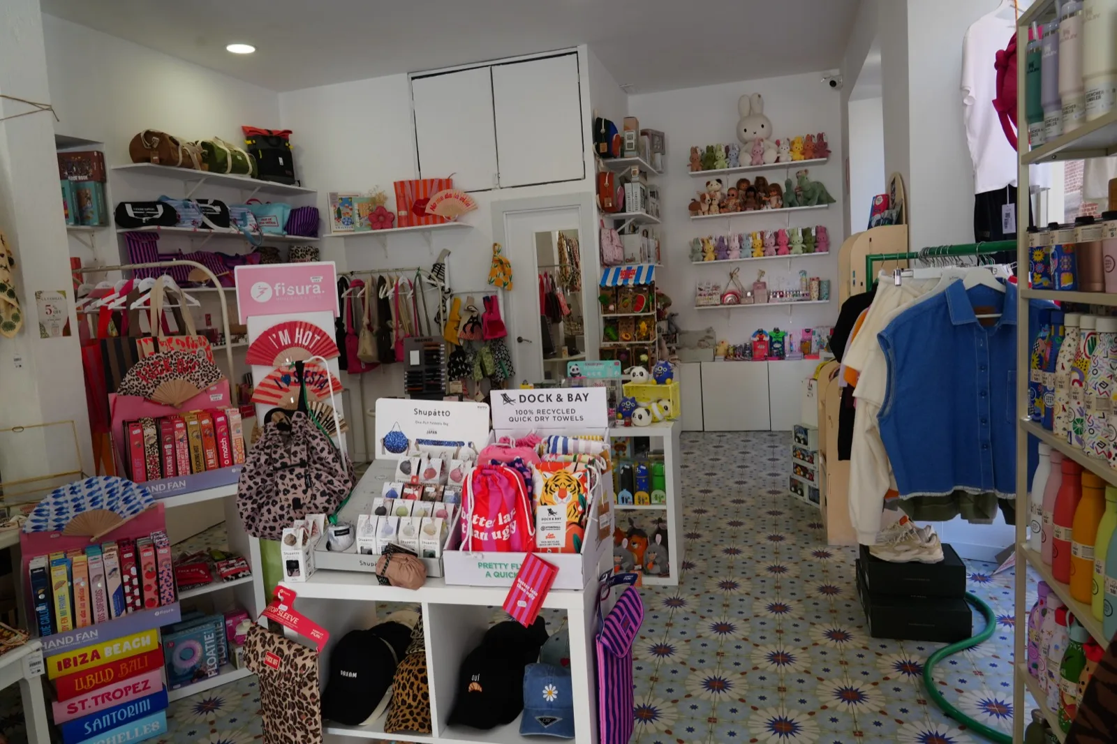 Inside La Familia Concept Store in Malaga, patterned tiled floor with shelves of fans, hats, toys and gifts