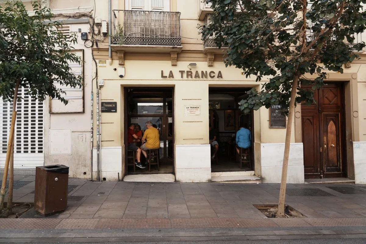 The cream facade of Bar La Tranca on Calle Carretería, two open doorways with people sitting at the counter just inside