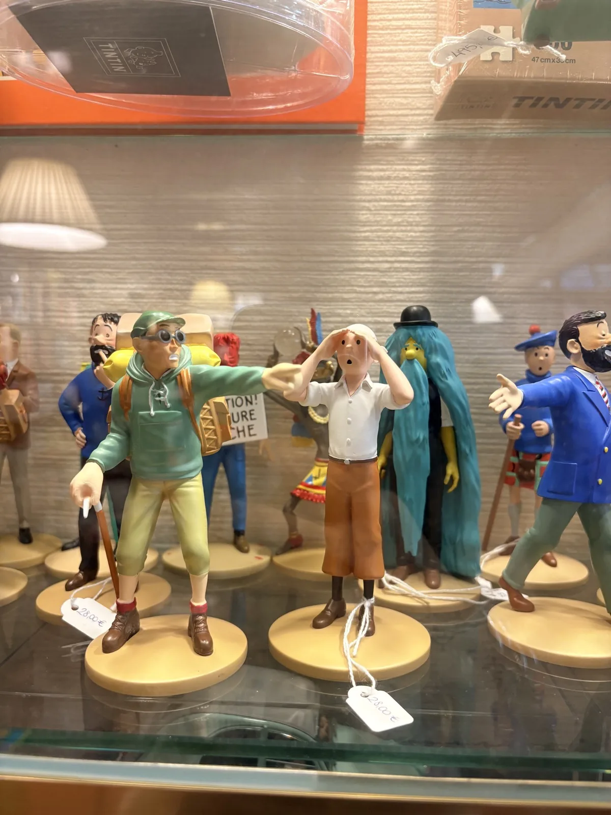 Tintin figurines displayed in a glass cabinet at Mapas y Compania in Malaga, including Tintin, Haddock and other characters with price tags