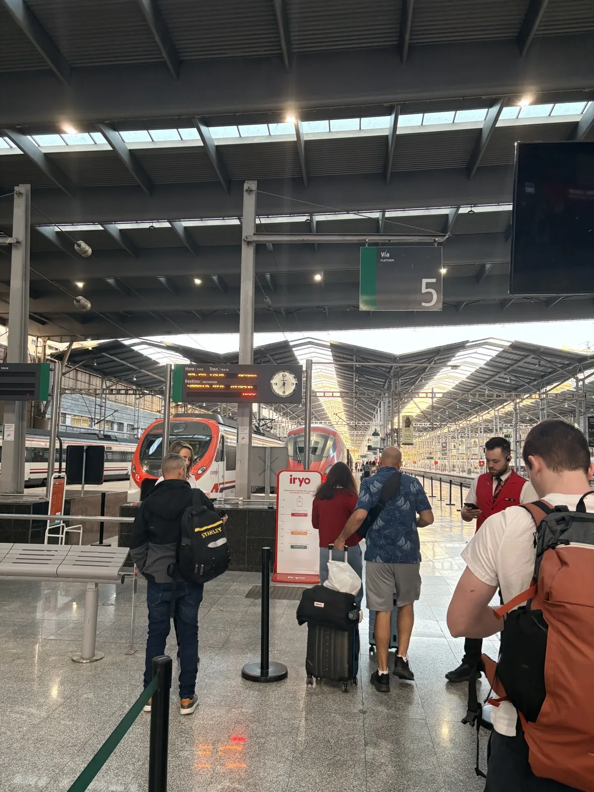 Trains waiting at platform 5 in Málaga María Zambrano station, with travellers and a conductor on the platform