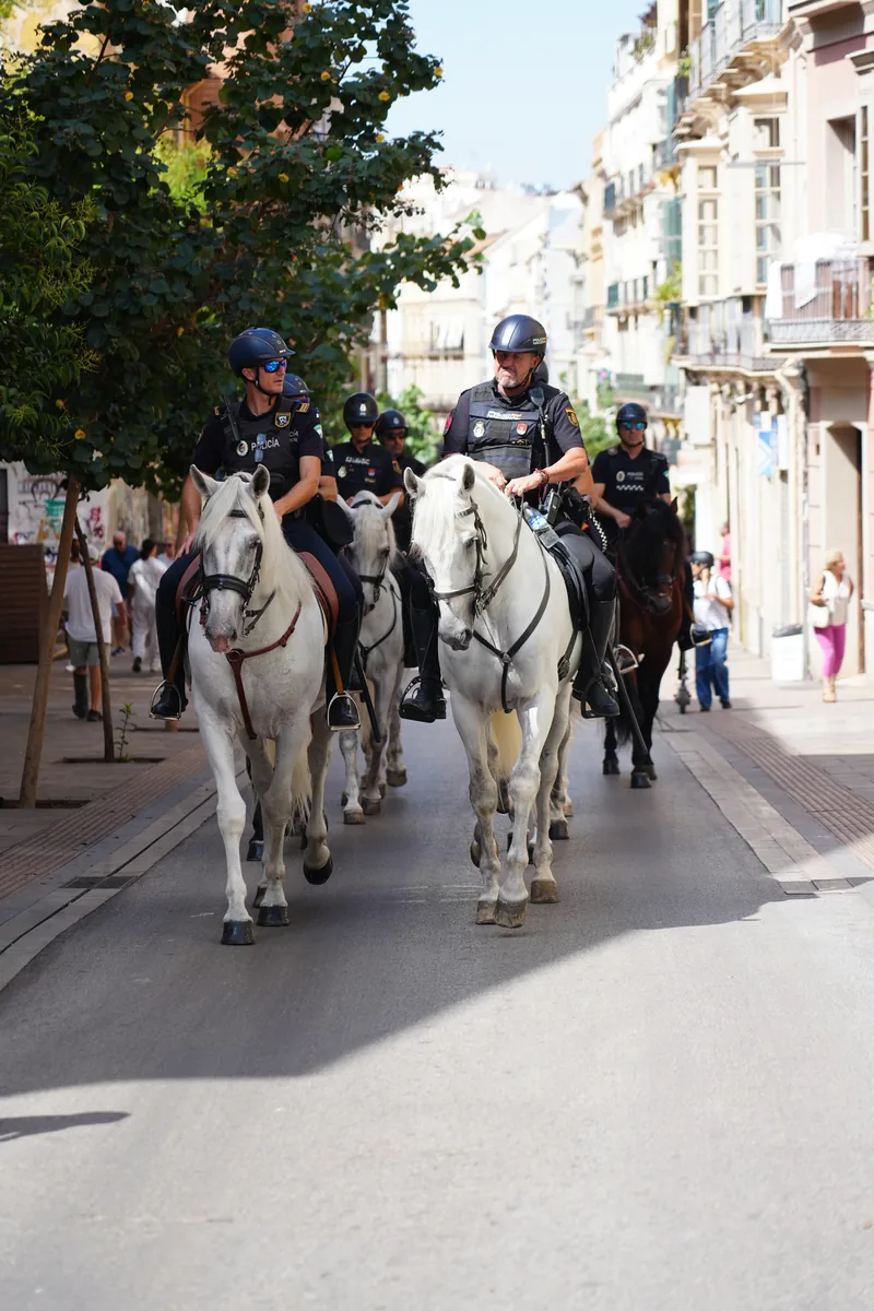 Two mounted police officers on horseback riding down a city street in Málaga