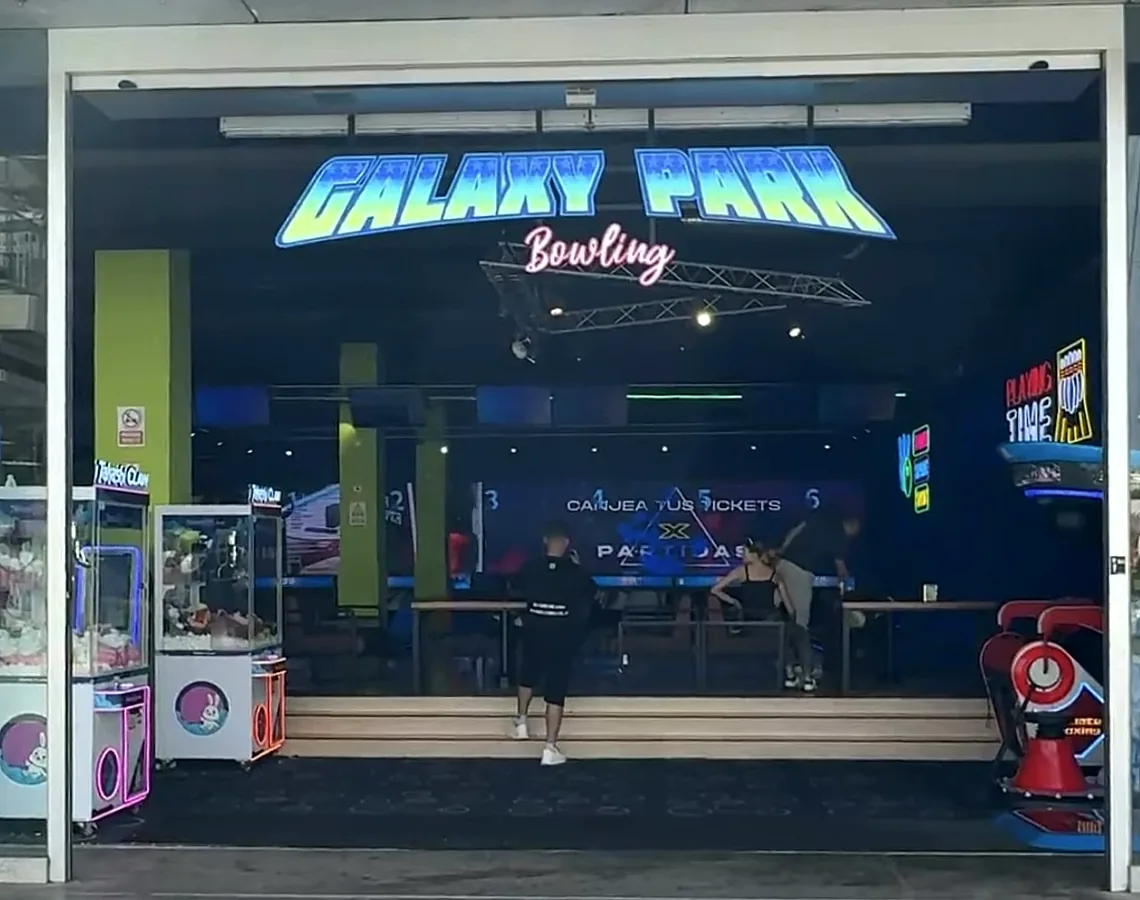 The neon Galaxy Park Bowling sign over the entrance to the arcade and bowling alley at Muelle Uno in Málaga, with claw machines by the door