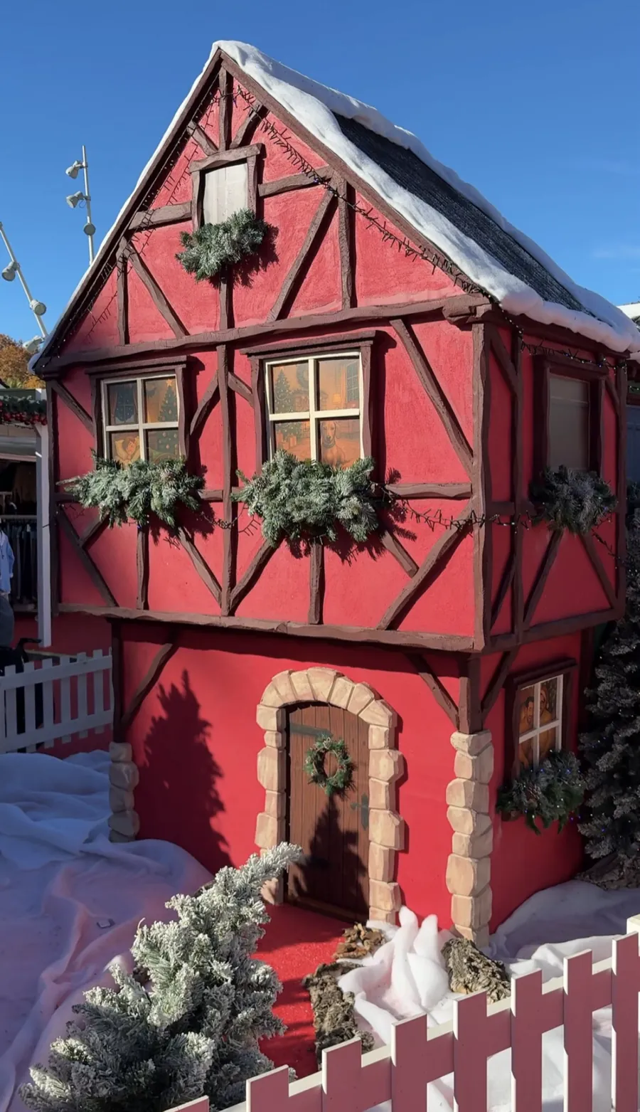 Decorated red gingerbread-style house display with fake snow at the Muelle Uno Christmas market in Malaga