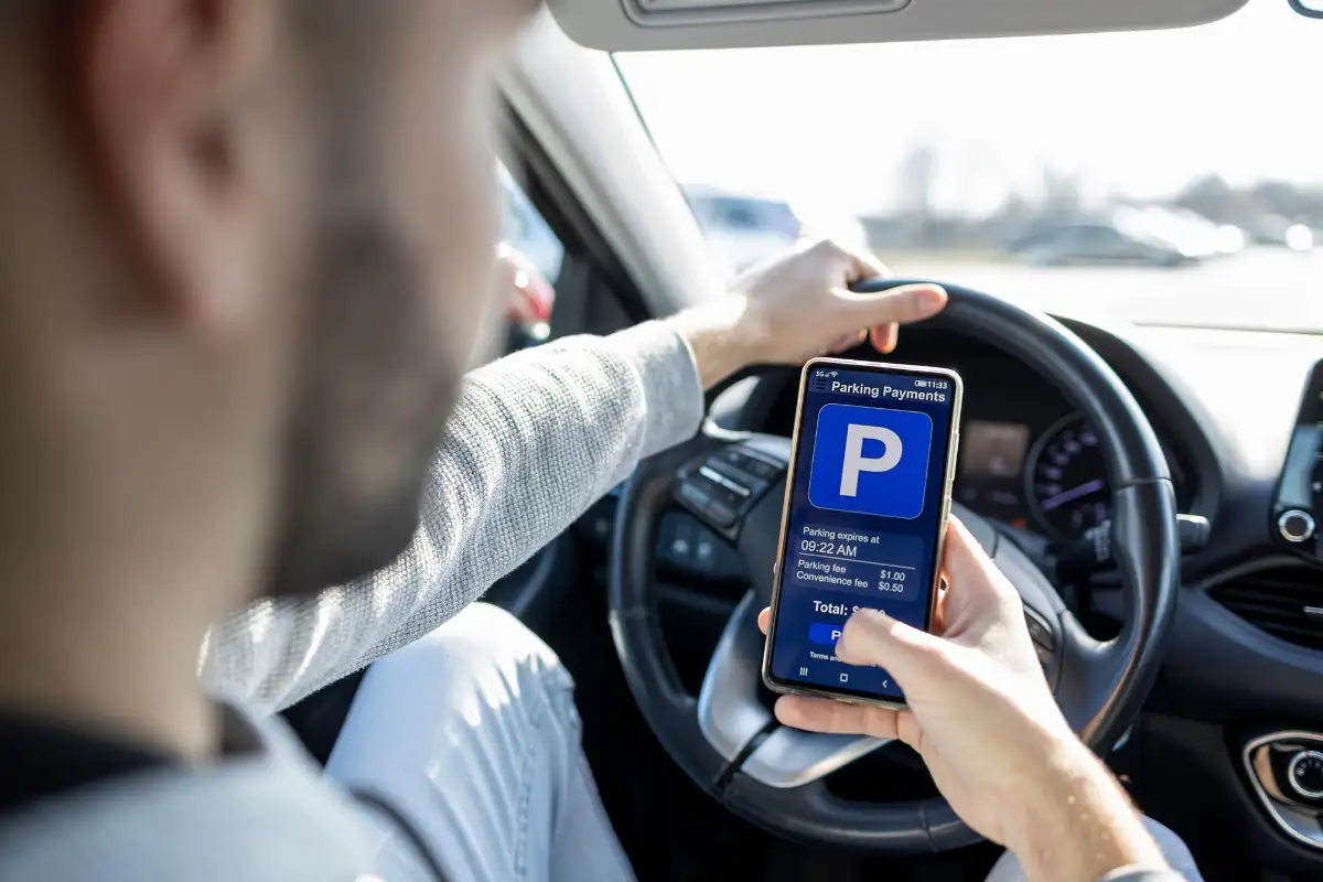 Driver using a parking payment app on their phone while sitting in a car in Málaga