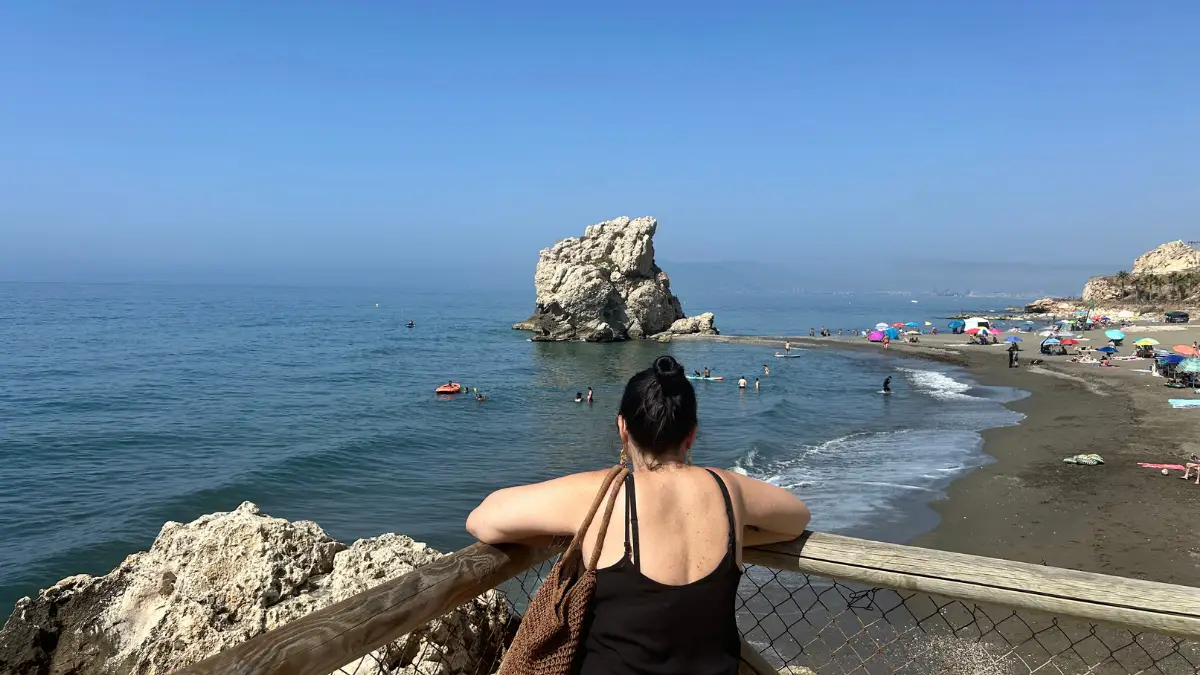 Woman looking out from a viewpoint over Playa del Peñón del Cuervo beach and the sea rock
