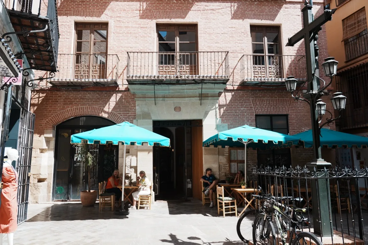 Turquoise umbrellas over the terrace tables outside Perro Viejo's brick-fronted building, diners at a table by the entrance