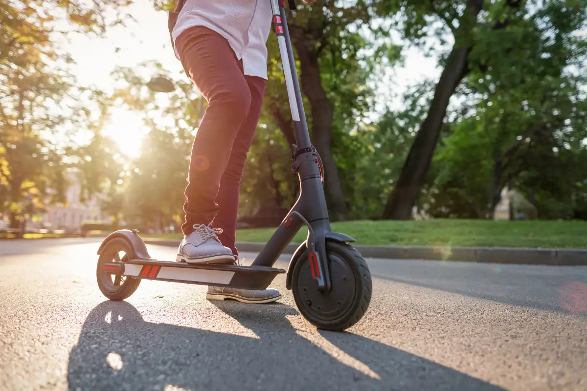Person riding an electric scooter along a sunny city path in Málaga