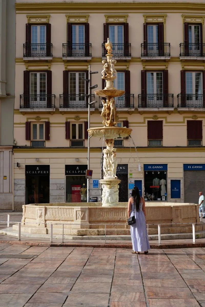 Heidi standing in front of the ornate fountain in Plaza de la Constitucion, Malaga