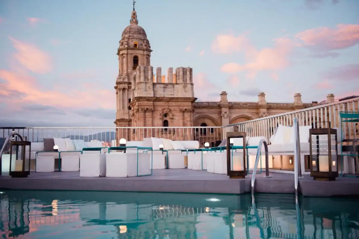 Rooftop pool and terrace at Hotel Molina Lario with Málaga Cathedral in the background at dusk