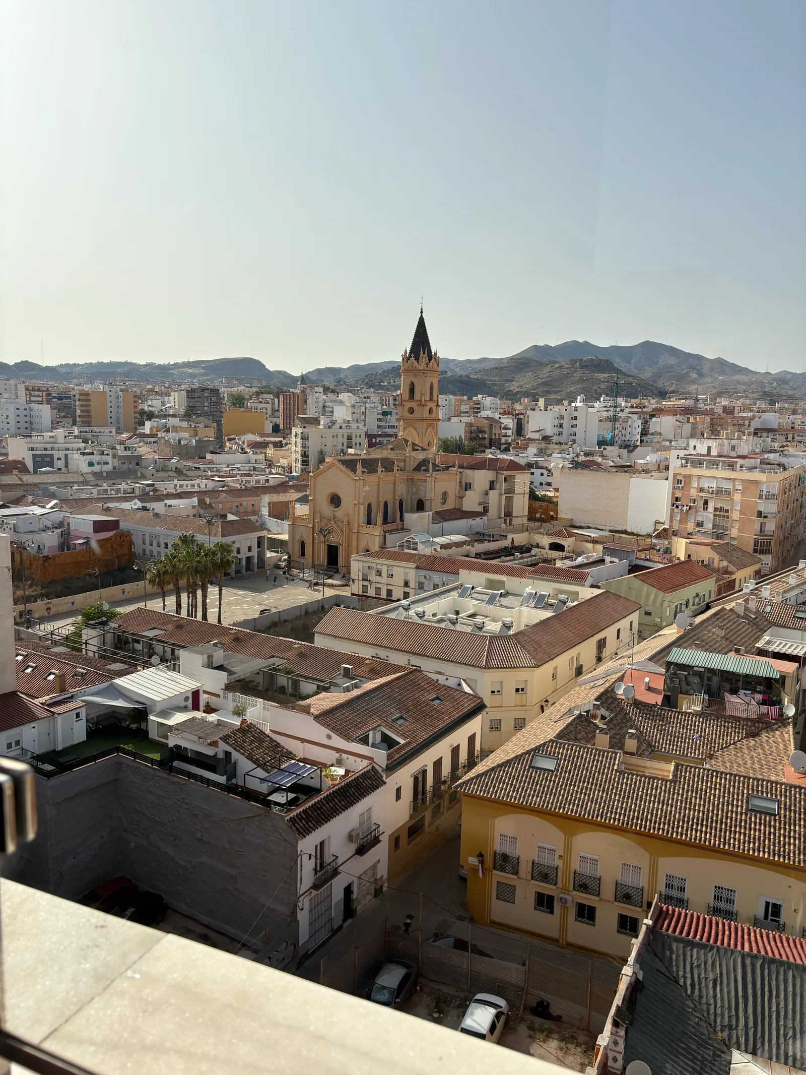 Rooftop view over Malaga with parked cars and terracotta rooftops below