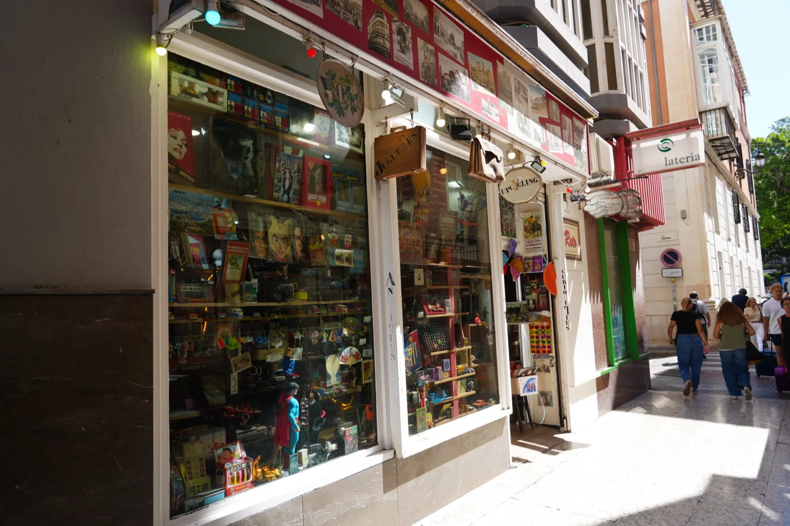 Roto antiques shop storefront window in Malaga, packed with toys, figurines and collectibles, the Roto sign visible on the awning