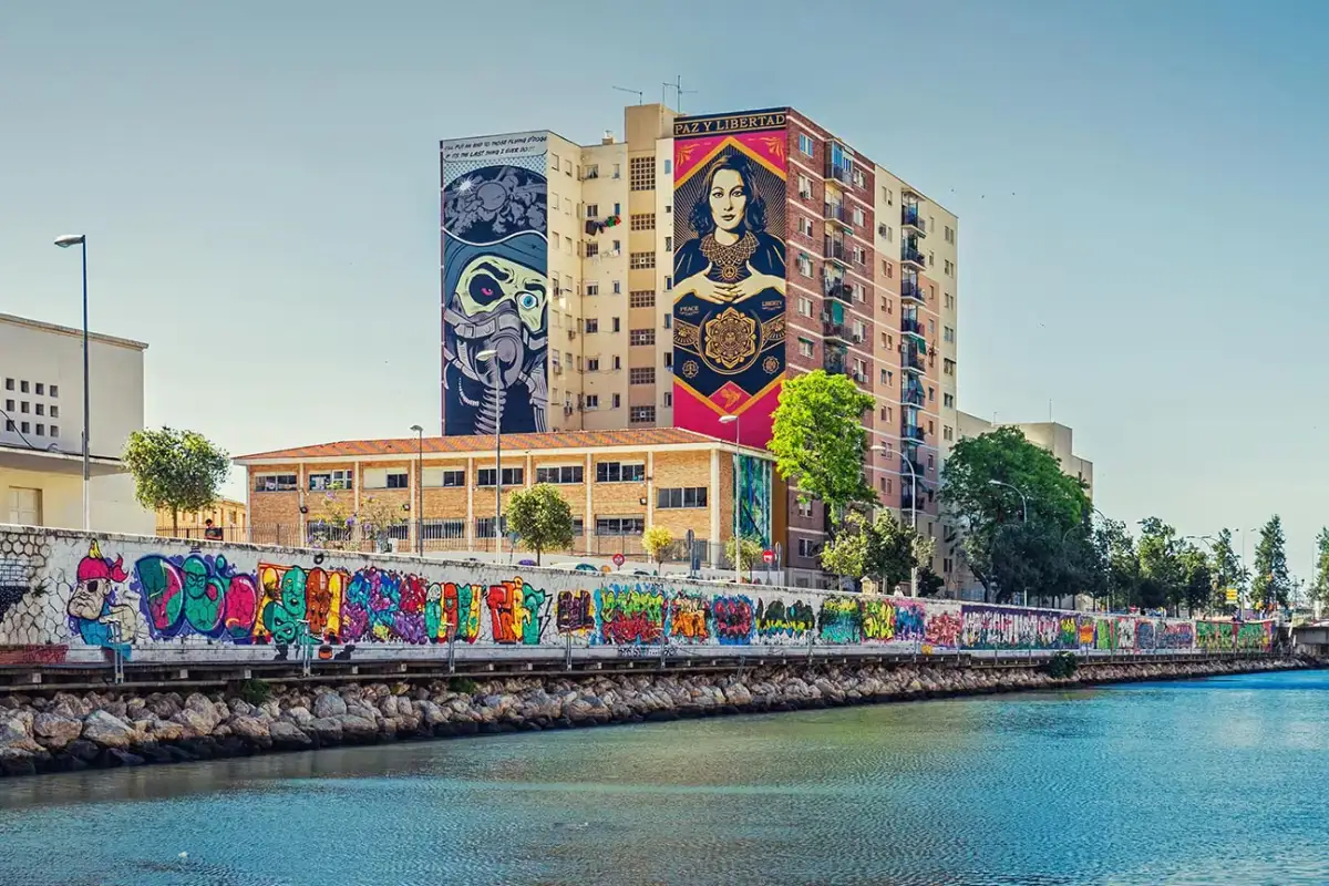 Large street art murals along the Guadalmedina riverbank in Malaga's Soho district