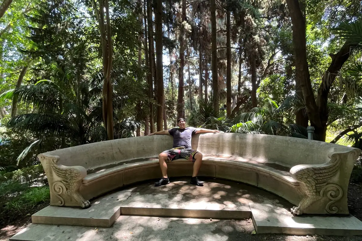 Man relaxing on a curved stone sofa in a shaded park in Málaga