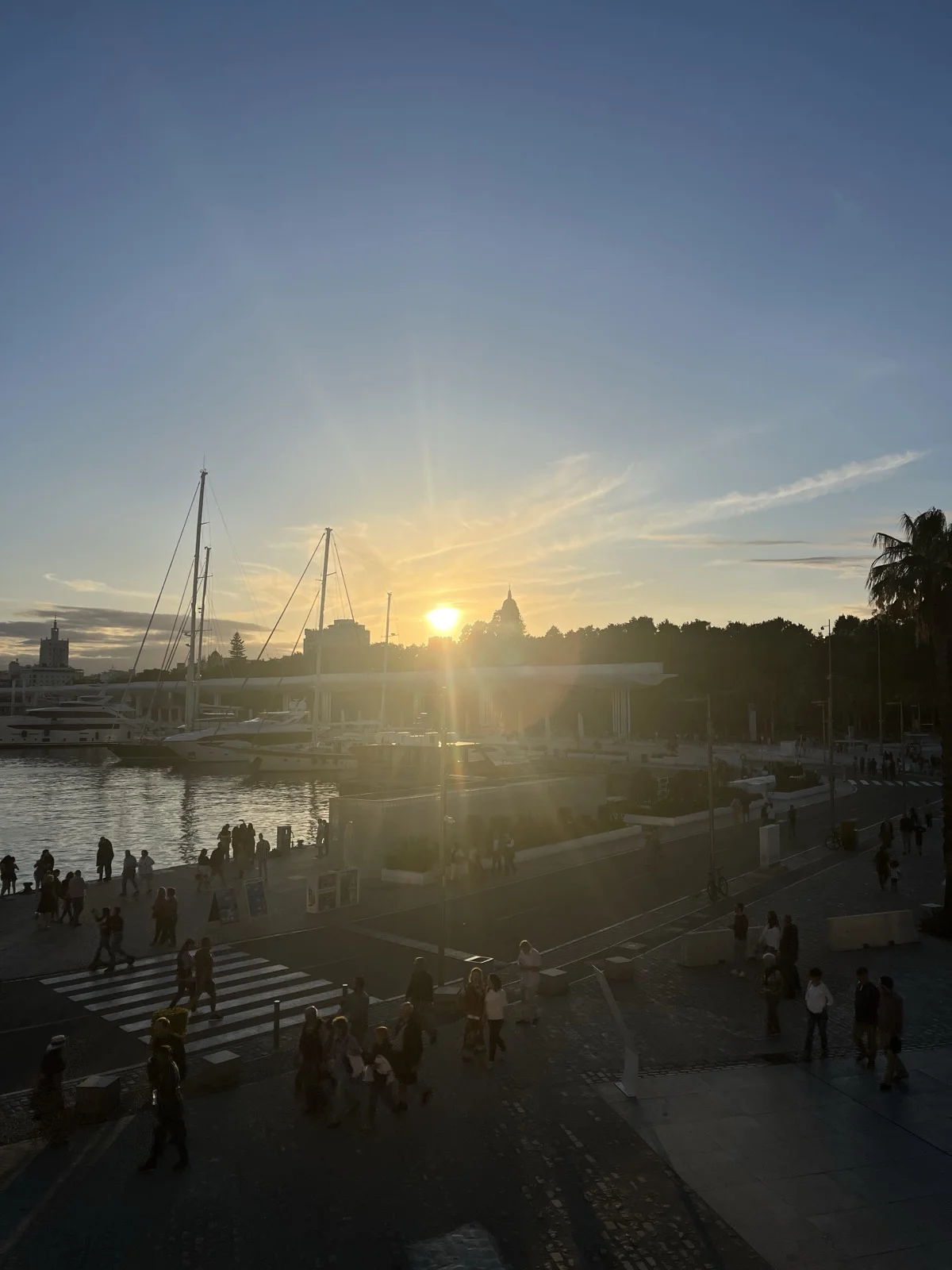 Sunset sun flare over Málaga marina with sailboat masts silhouetted