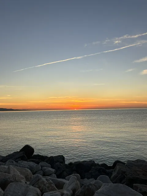 The winter sun dropping straight into the sea rather than behind the mountains, seen from the rocks of a breakwater on Málaga's eastern beaches