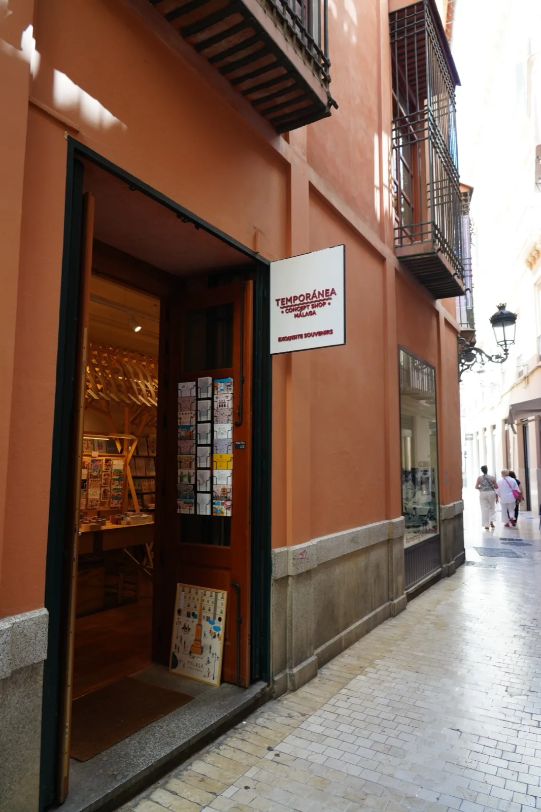 Temporanea Concept Shop entrance in Malaga, orange building facade with the shop sign and postcards visible through the open door