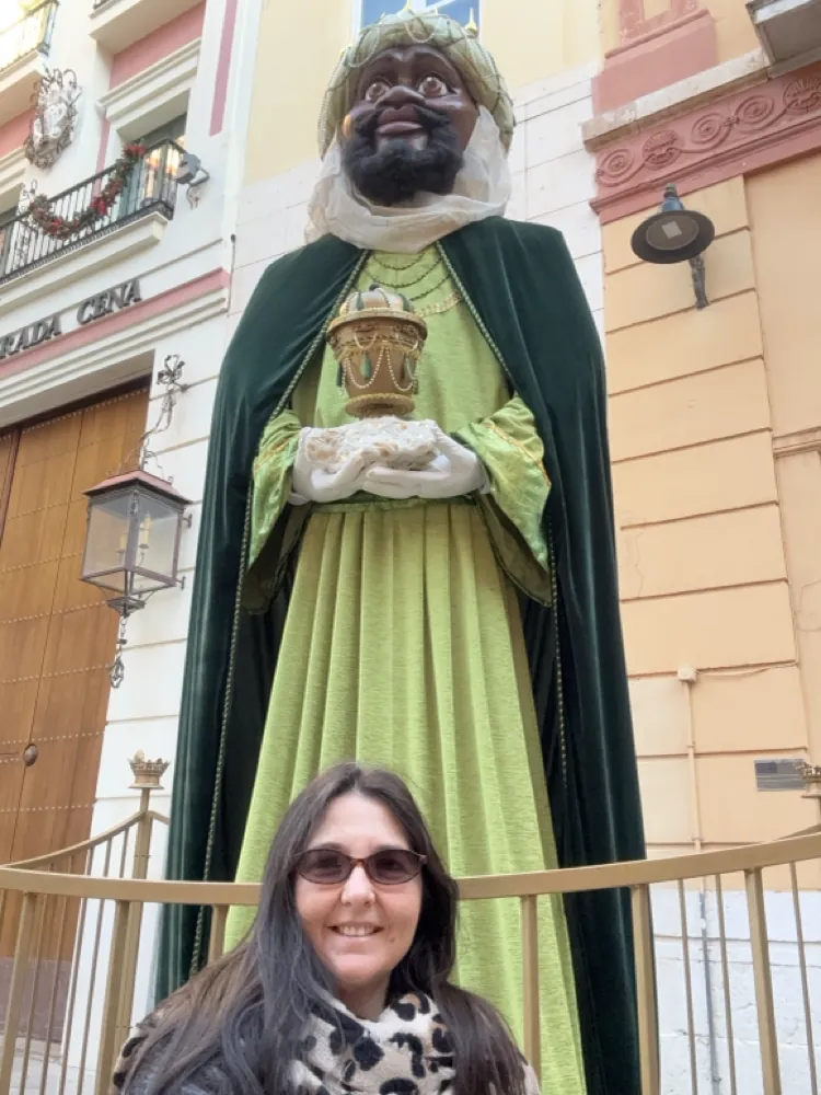 Heidi smiling next to the giant Baltasar statue in dark green robes on a Malaga street