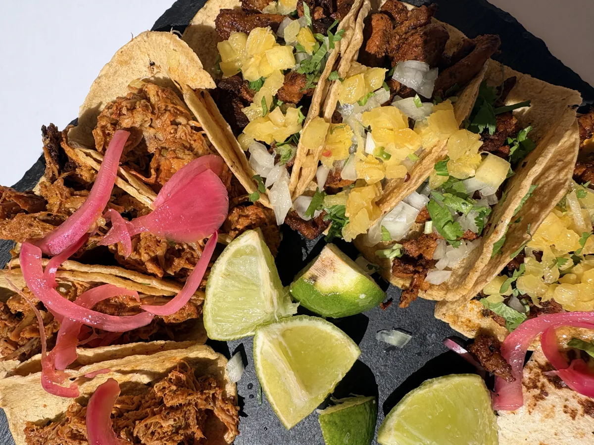 A platter of tacos al pastor with pineapple, onion and cilantro, pulled pork tacos with pickled red onion, and lime wedges, at TKO Tacos in Málaga