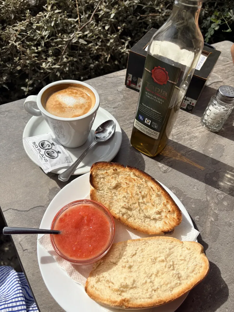 Toast with crushed tomato, olive oil and a café con leche at an outdoor table in Málaga