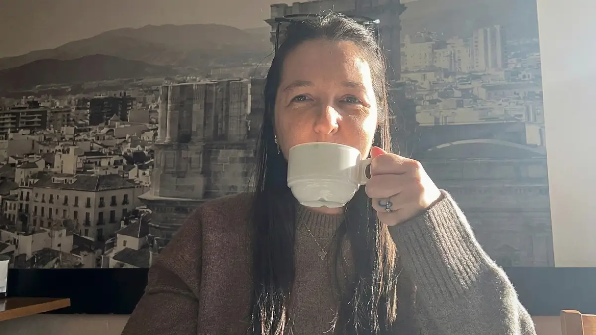 A woman drinking coffee at a café table in Málaga