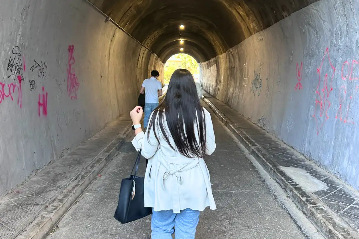 Woman walking alone through a stone archway tunnel in a Spanish town
