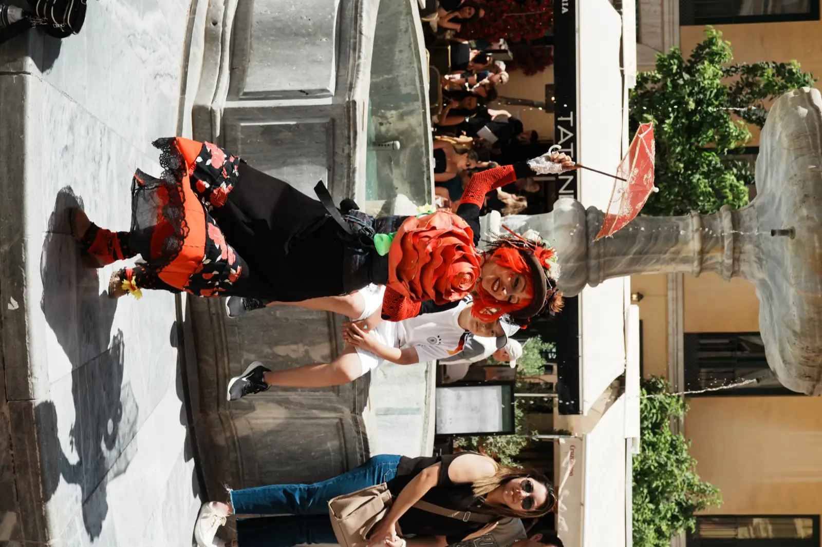 Costumed Carnival performer with a red rose parasol in a Málaga square