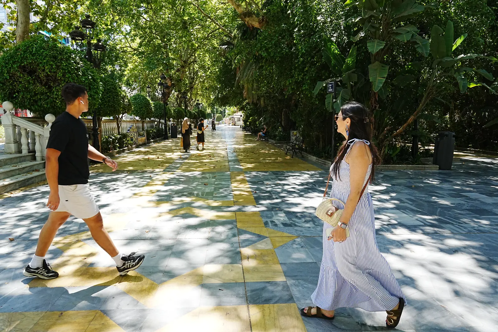 Couple walking the tiled path under shade trees in Alameda Park, Marbella
