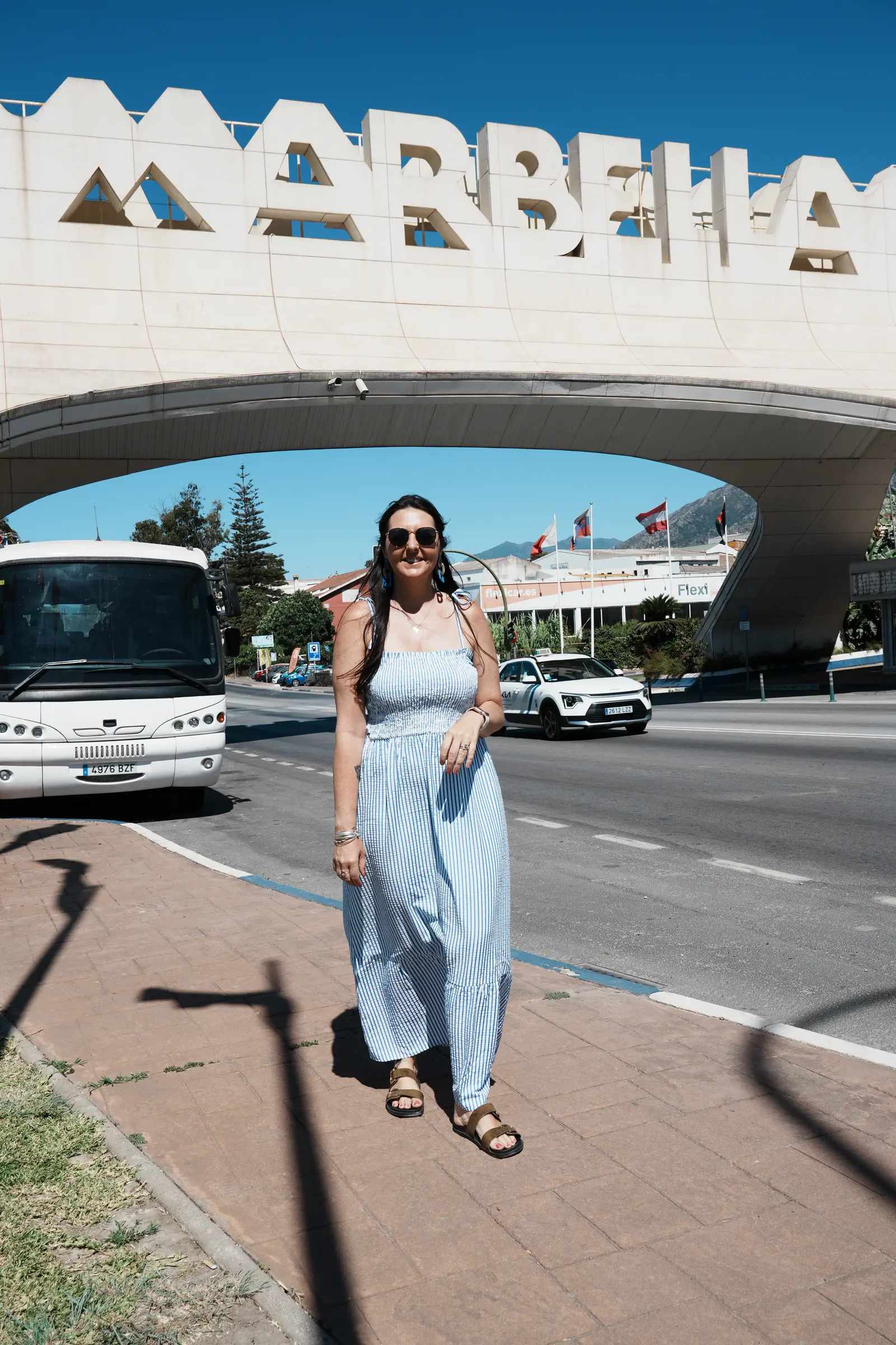 Woman under the white Marbella arch monument on the approach into town