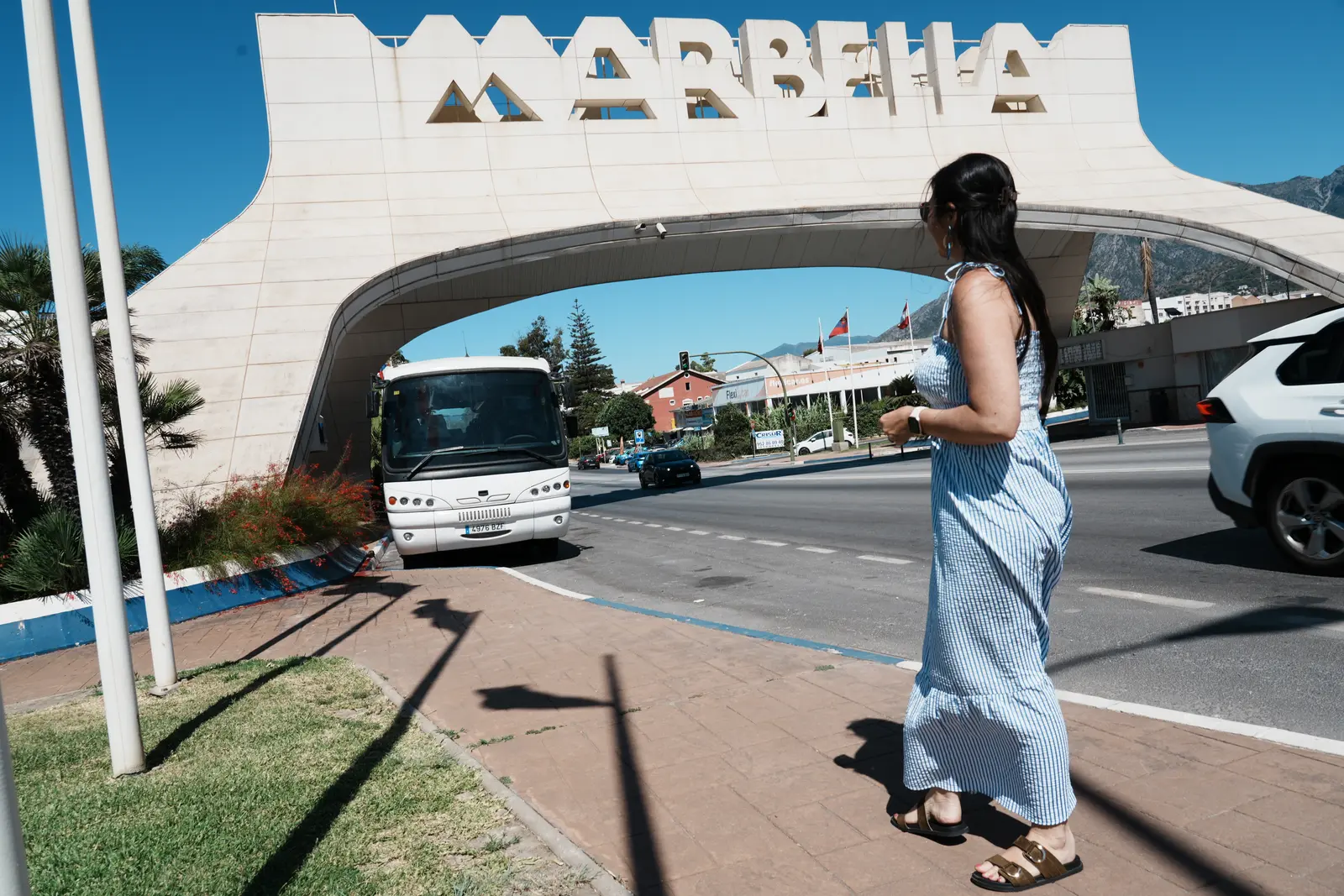 A woman walking beneath the Marbella sign in Marbella.