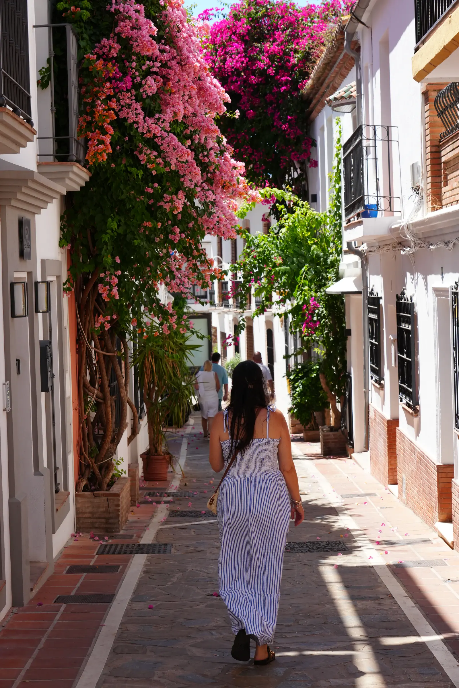 Woman walking through a bougainvillea-covered alley in Marbella