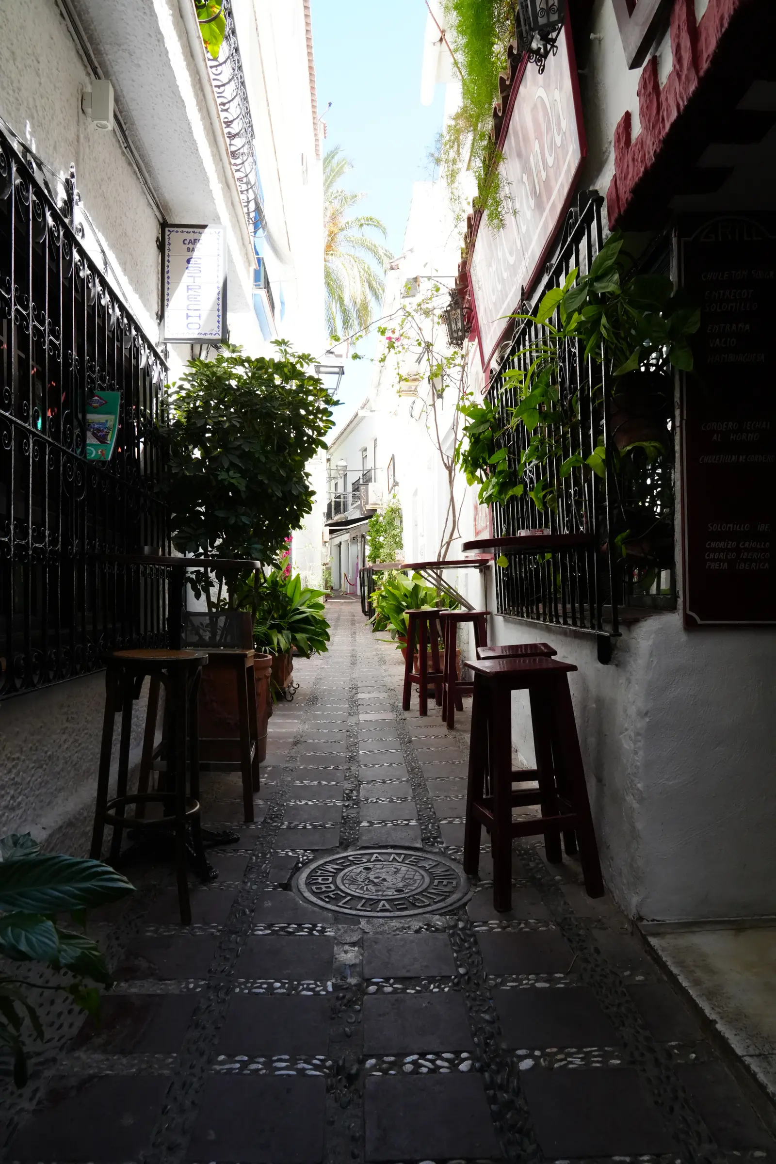 Stools and small tables outside Cafe Bar El Estrecho in the narrow shaded alley of Calle San Lazaro in Marbella