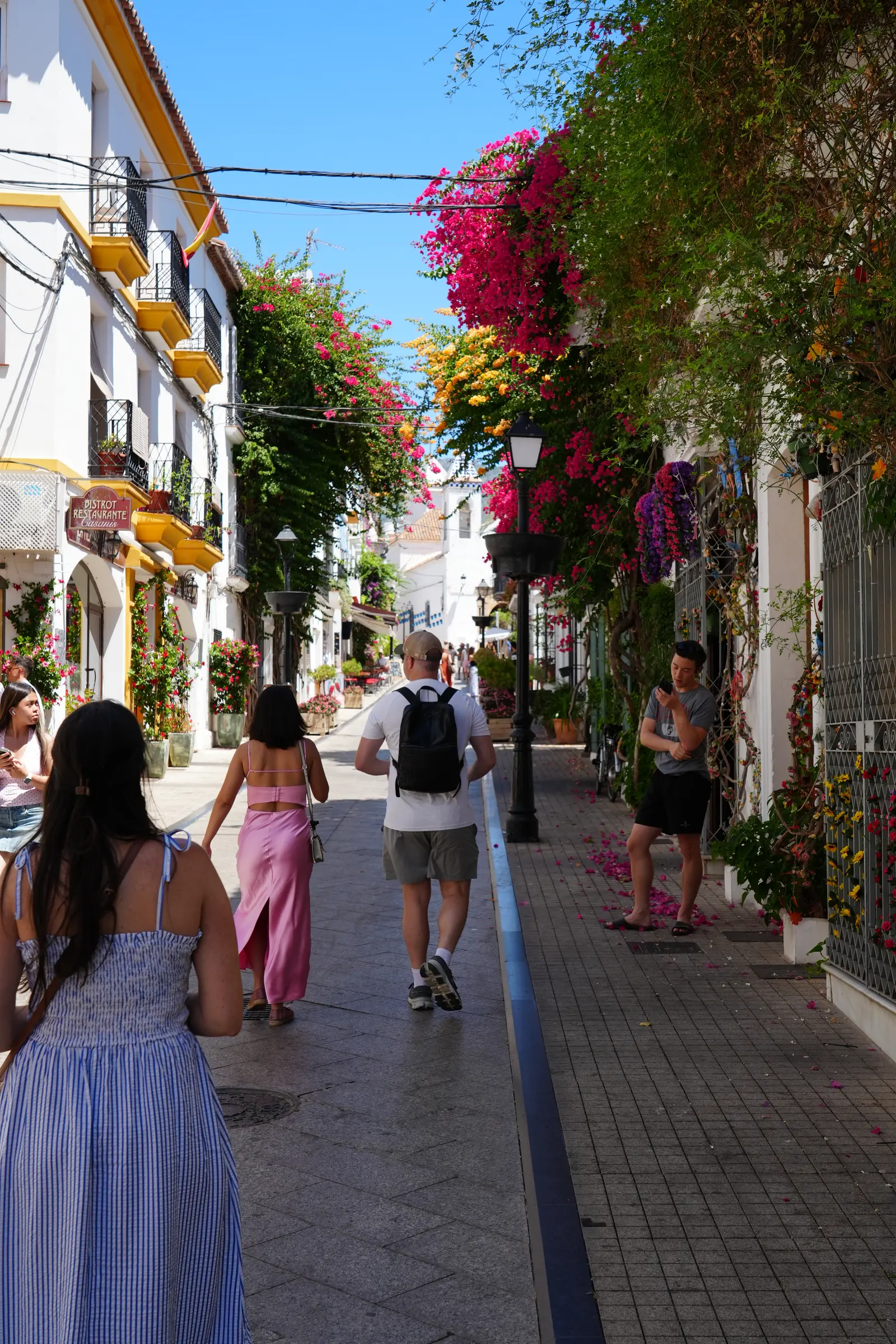 Heidi walking down a colourful street lined with bougainvillea in Marbella