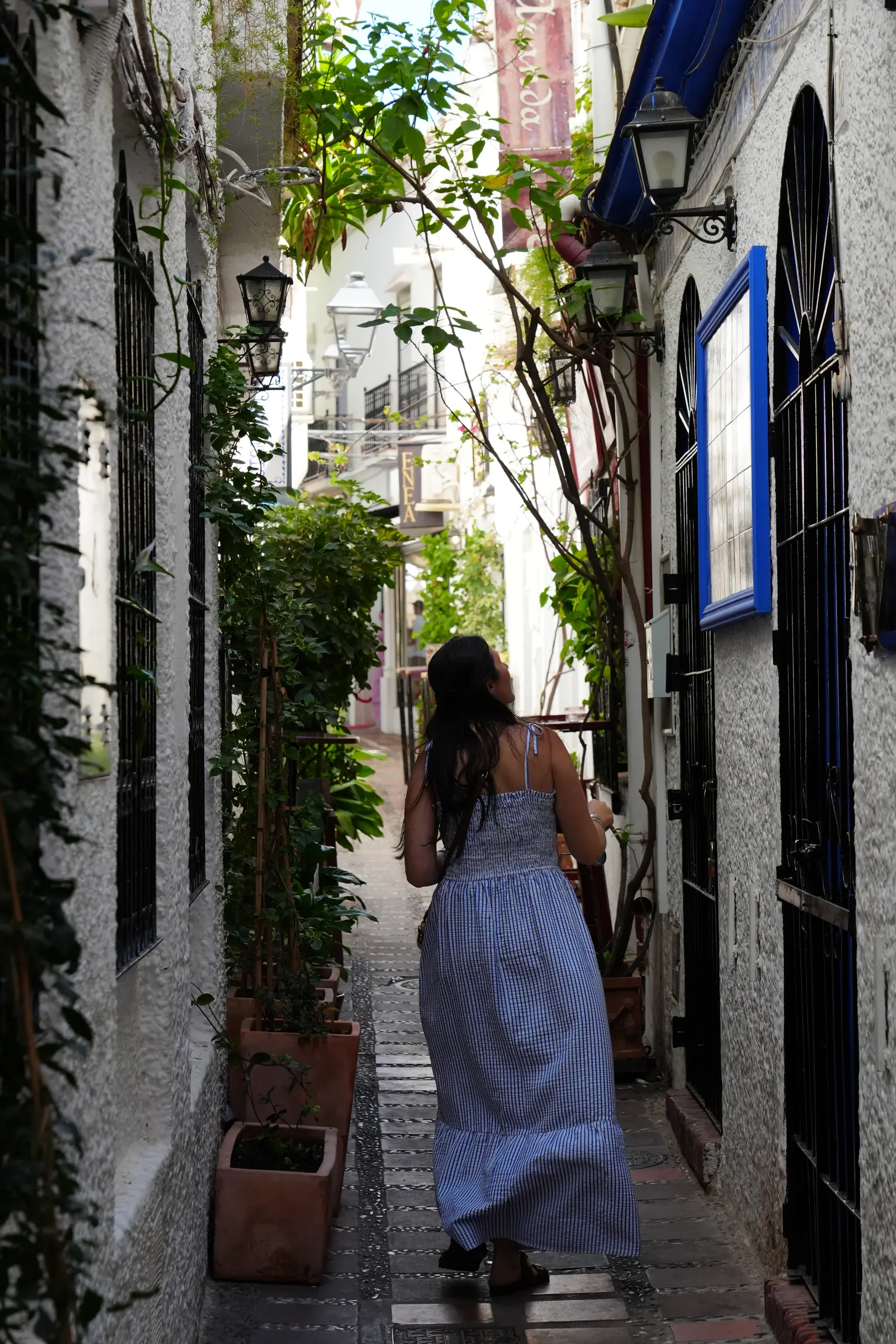 Heidi walking through a narrow greenery-lined alley in Marbella Old Town