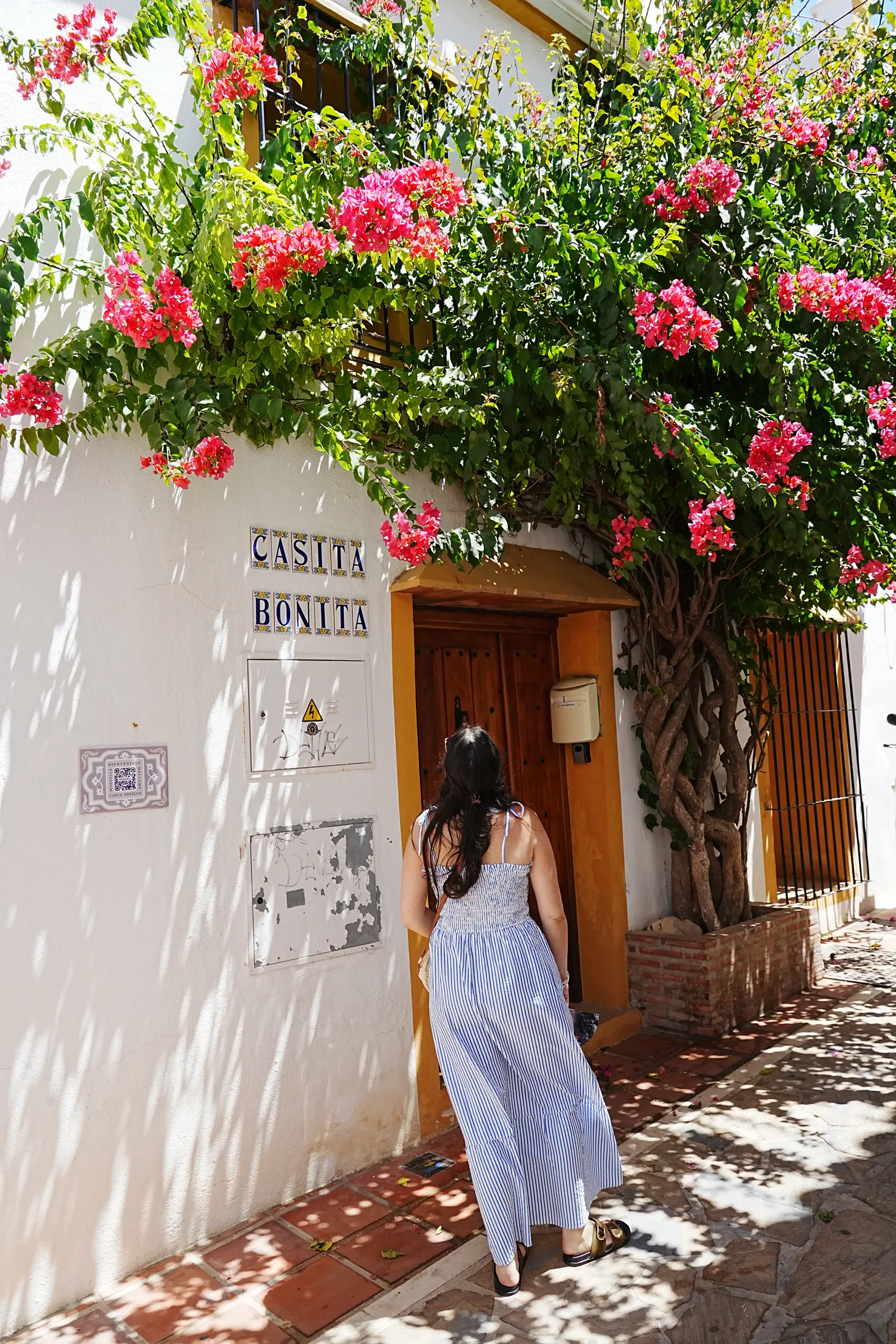 Woman looking up at bougainvillea in a Marbella Old Town doorway