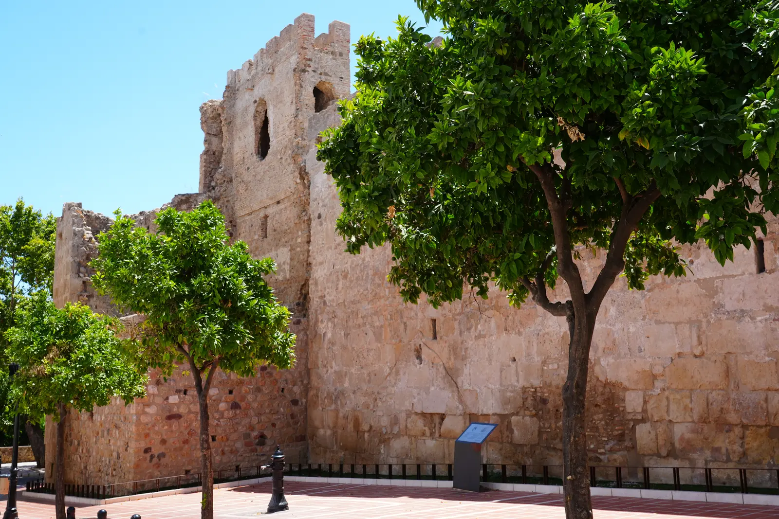 Crenellated 10th-century Moorish castle walls with orange trees in Marbella Old Town