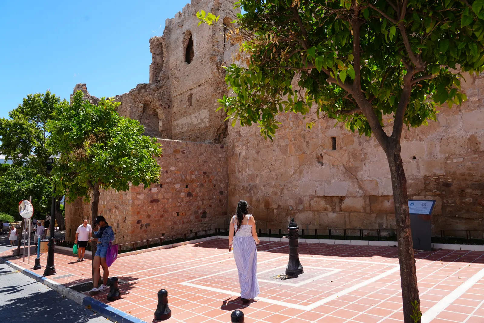 A woman standing in front of a castle wall in Marbella.