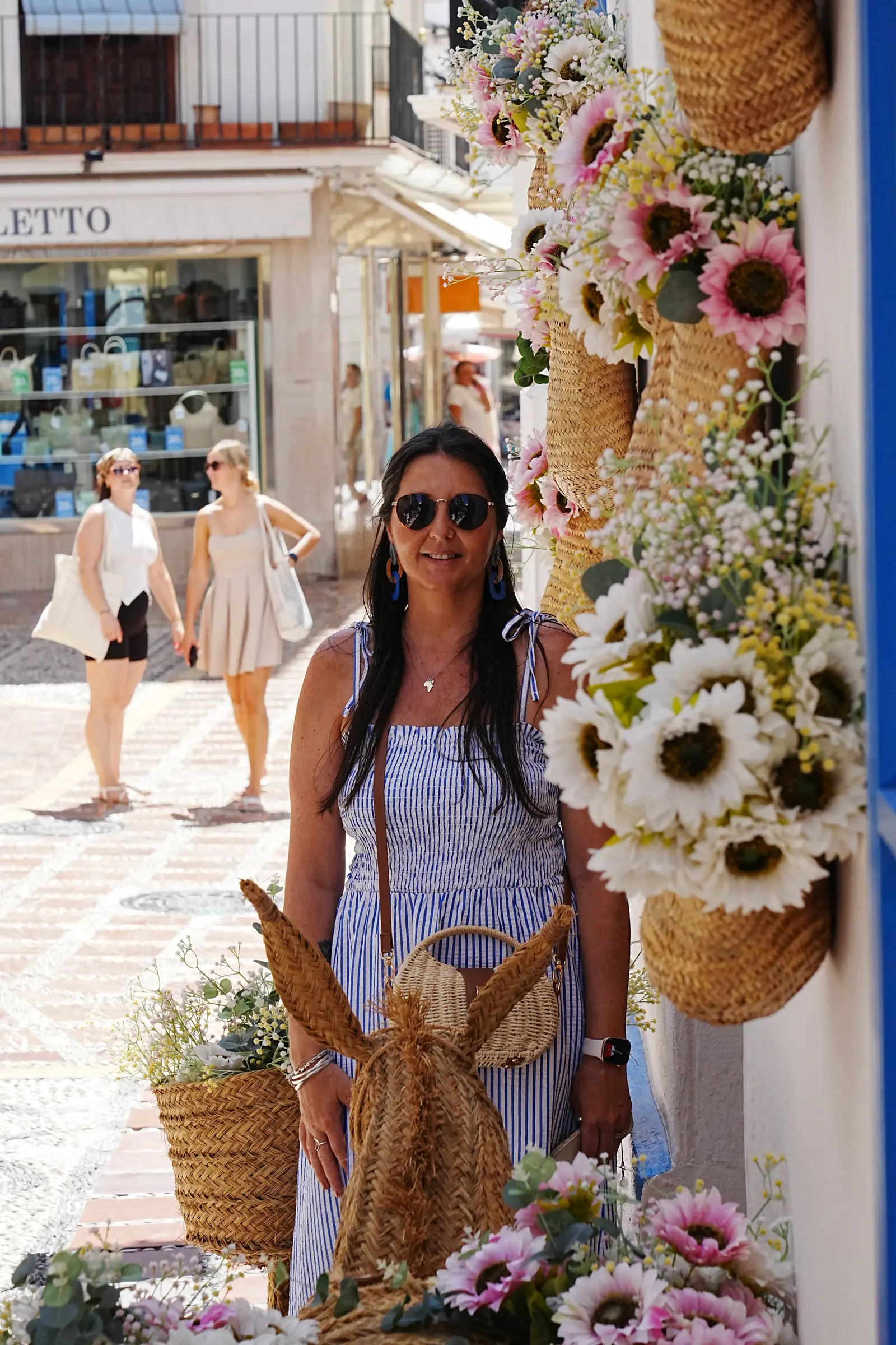 heidi standing next to some artificial flowers on a wall in a basket.