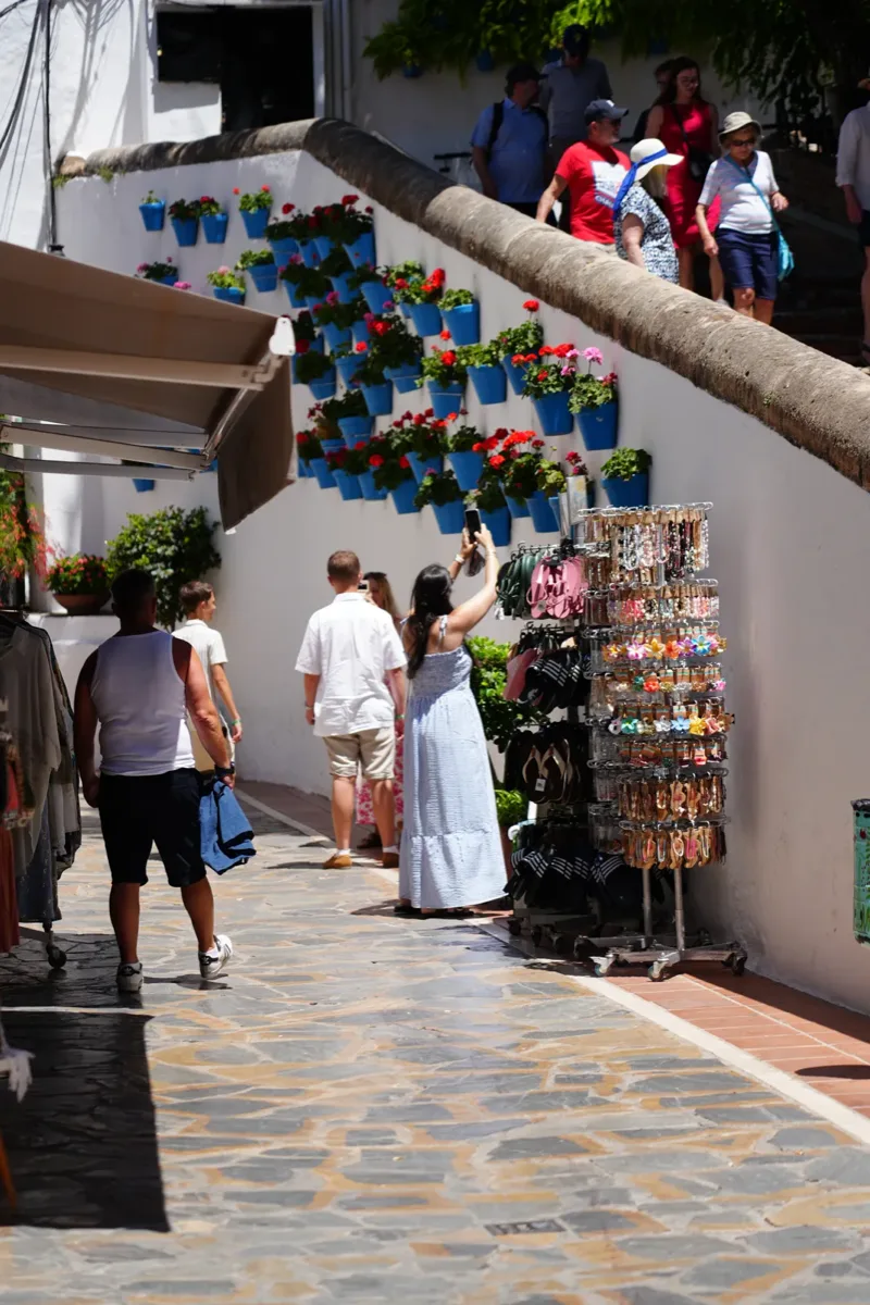 Heidi photographing blue flower pots hanging on a whitewashed wall in Marbella