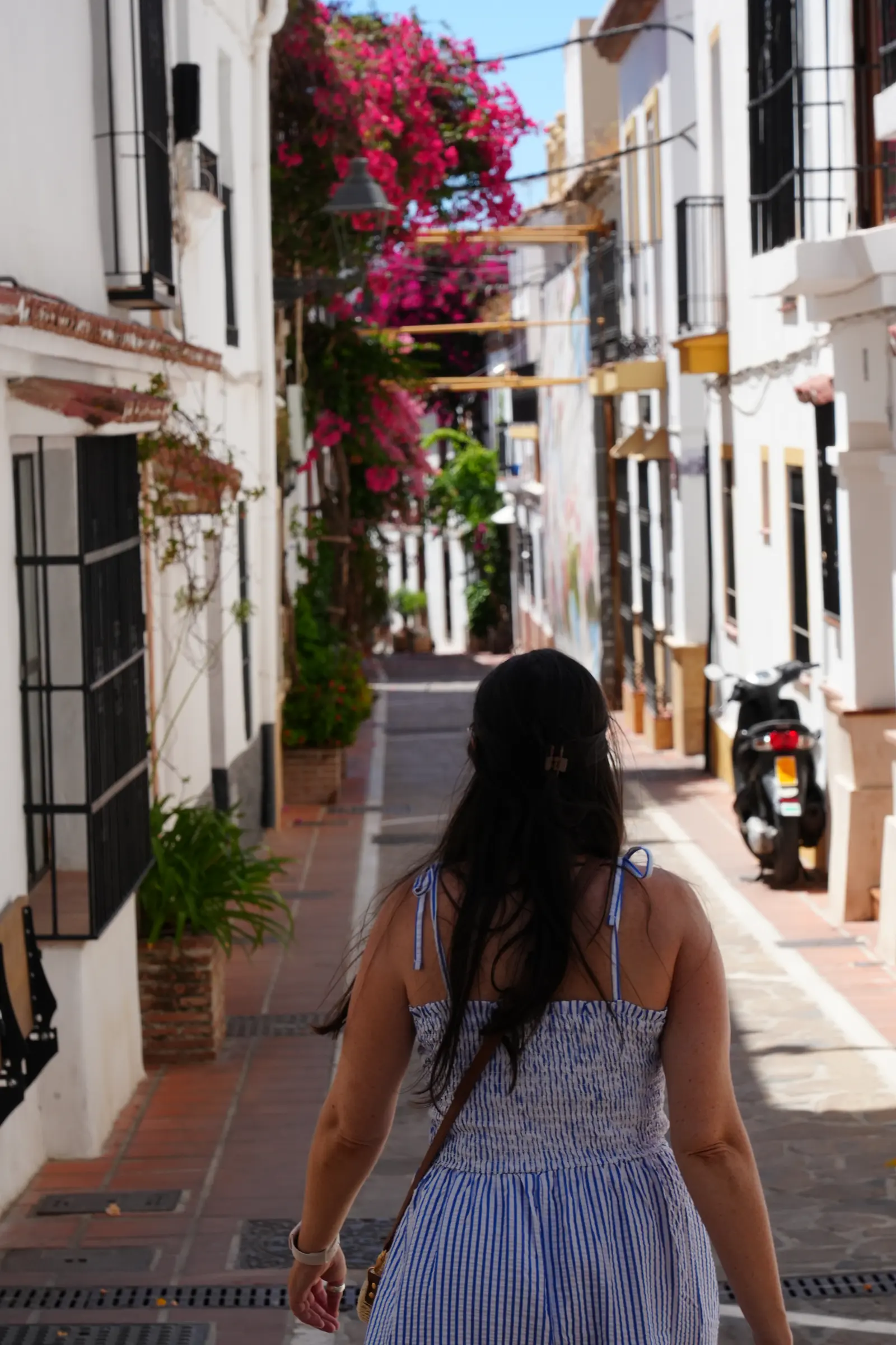Heidi is walking down a residential street in Marbella, covered in bougainvillea