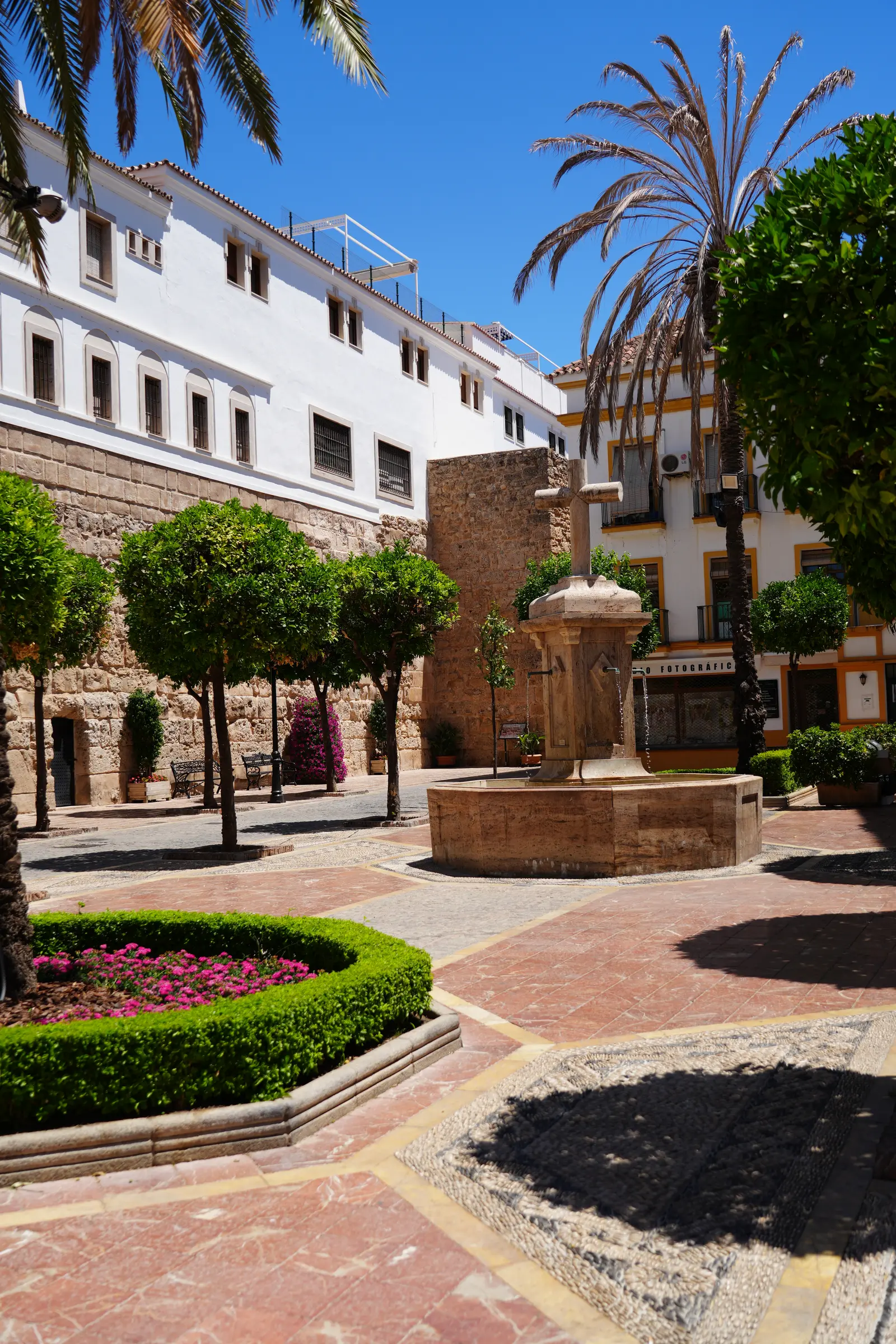The cross fountain and the old castle wall at Plaza de la Iglesia in Marbella