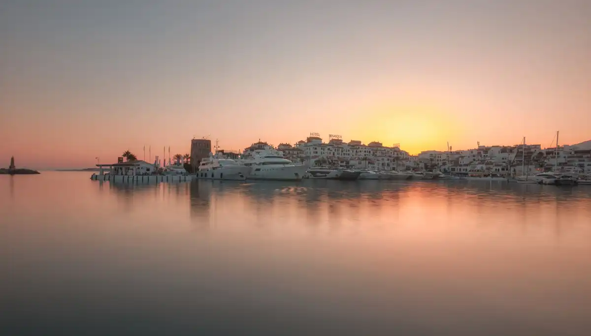 Sunset over Puerto Banús marina in Marbella with yachts reflected in calm water