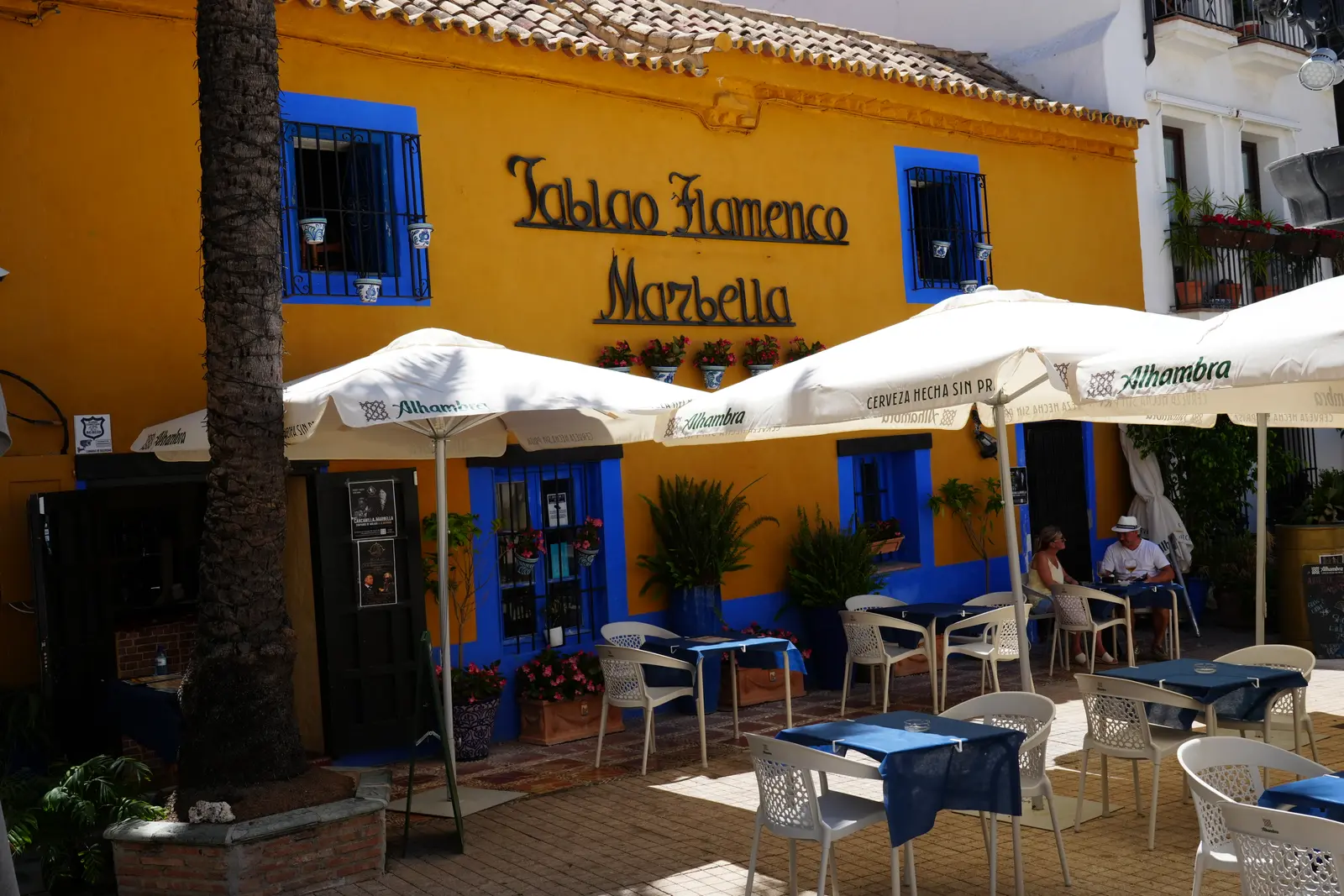 yellow wall with blue dors and windowframes with the sign tablao flamenco on it