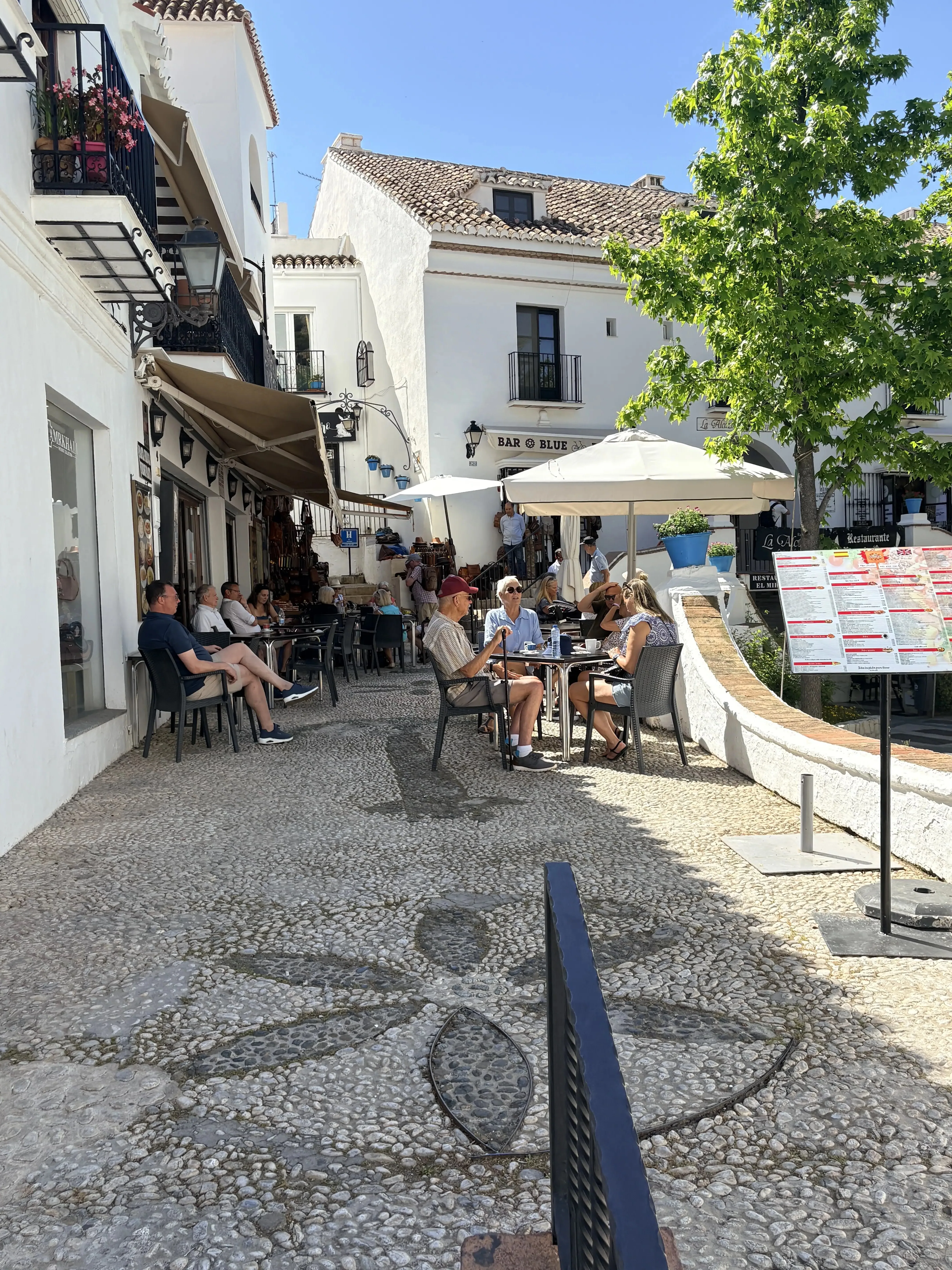 Outdoor restaurant tables on a cobblestone street in Mijas Pueblo