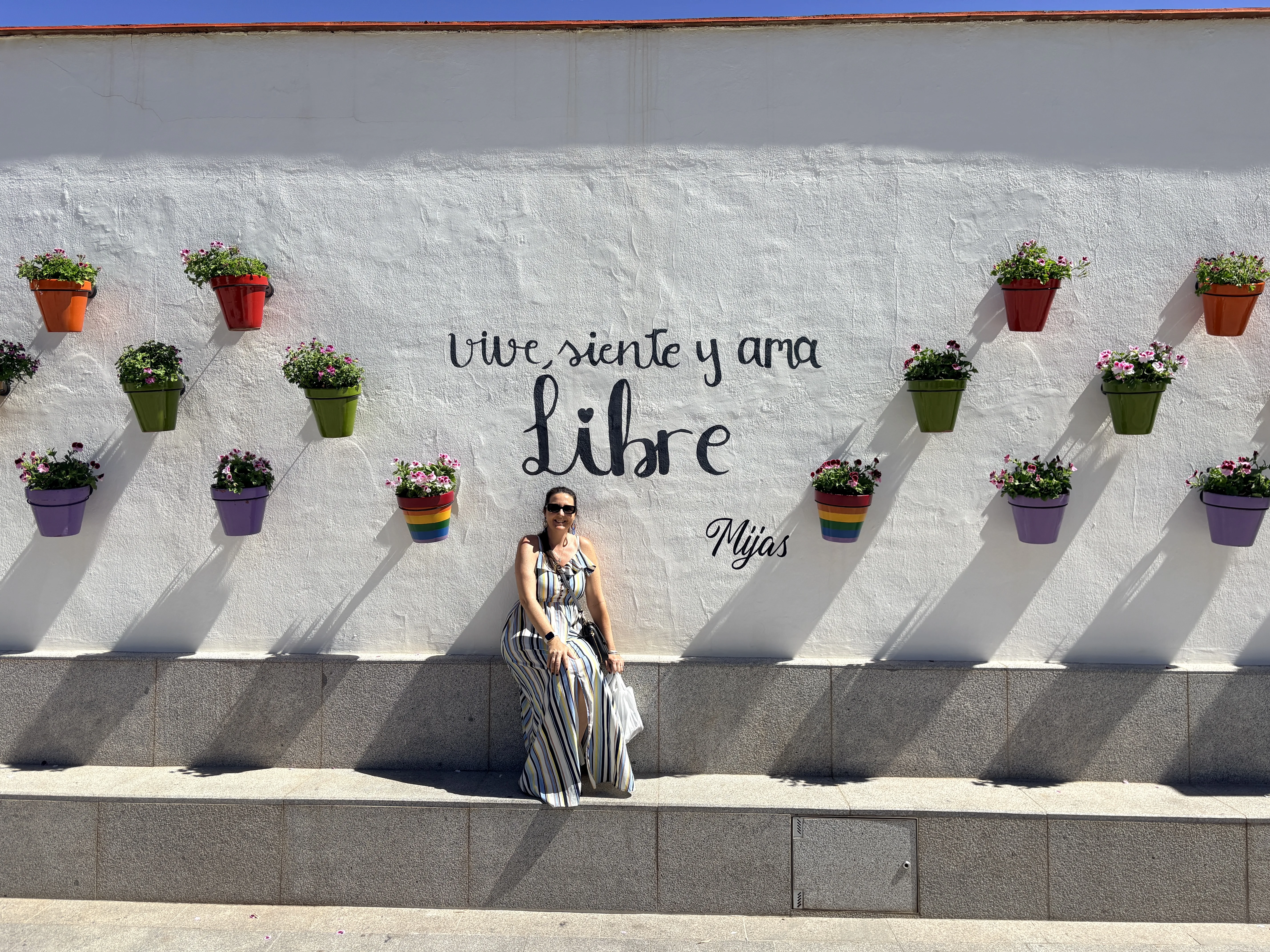 Woman posing in front of the Vive Siente Ama Libre street art mural in Mijas Pueblo