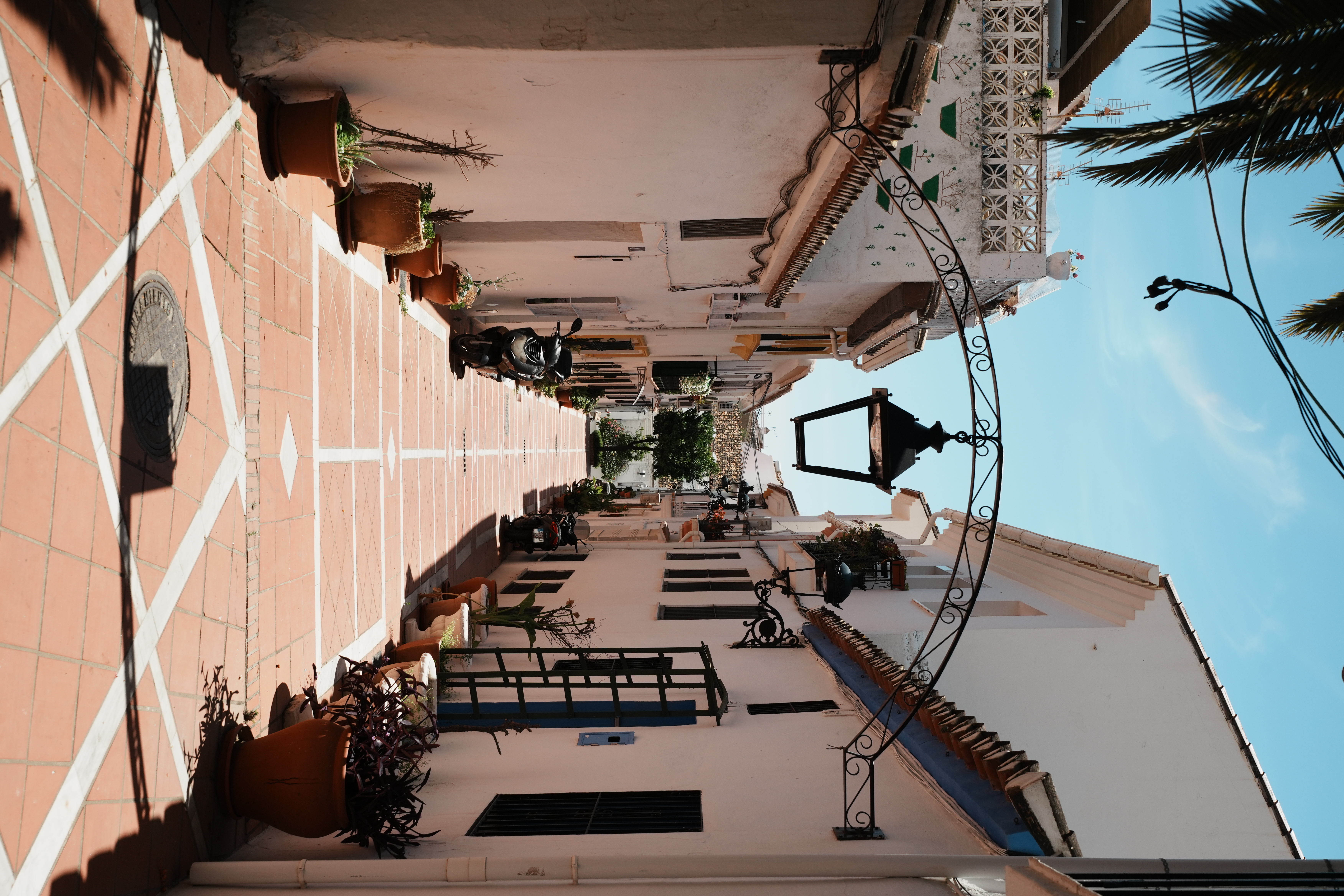 A narrow whitewashed street lined with plant pots in Benalmadena Pueblo