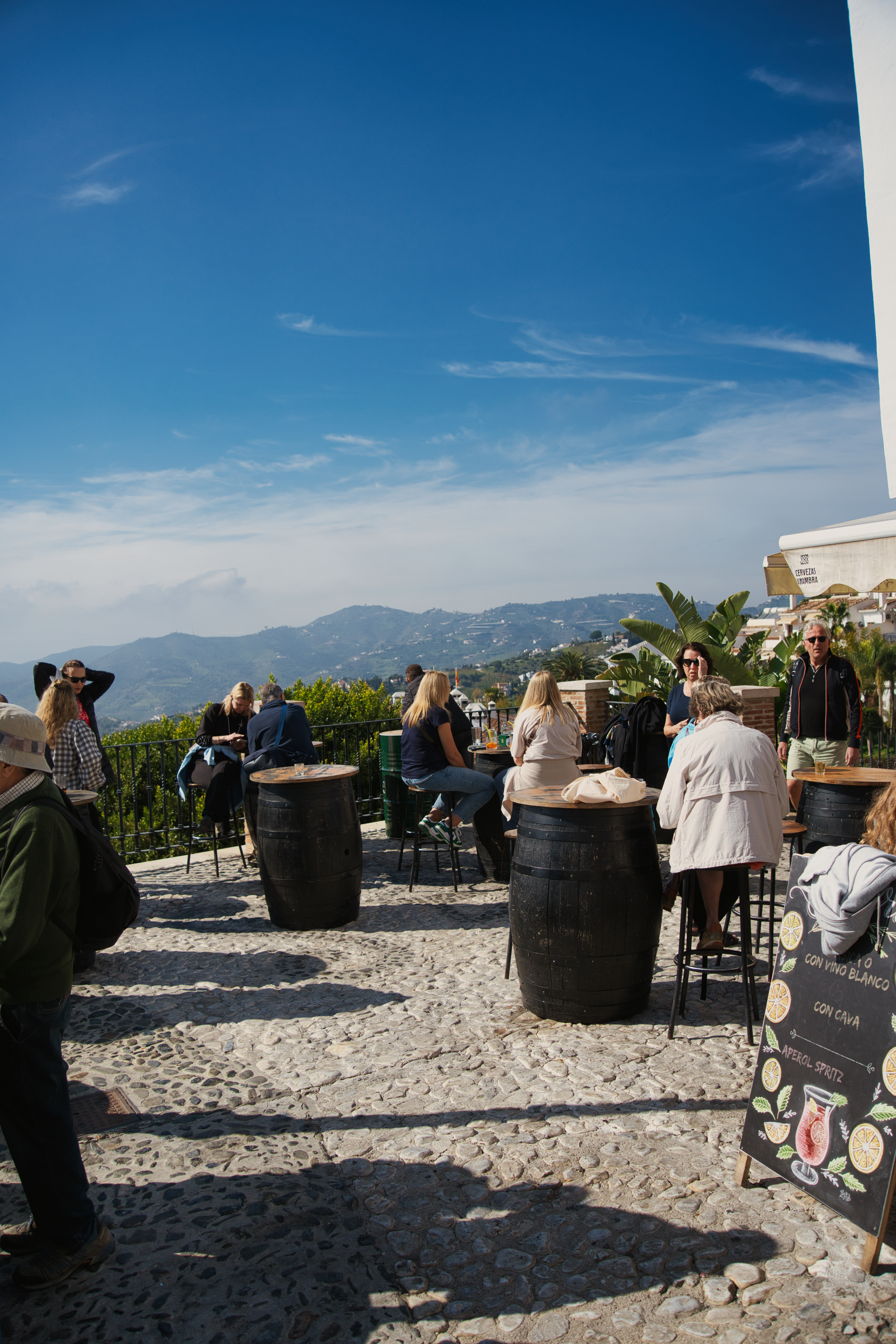 A hillside terrace bar in Frigiliana with barrel tables and mountain views