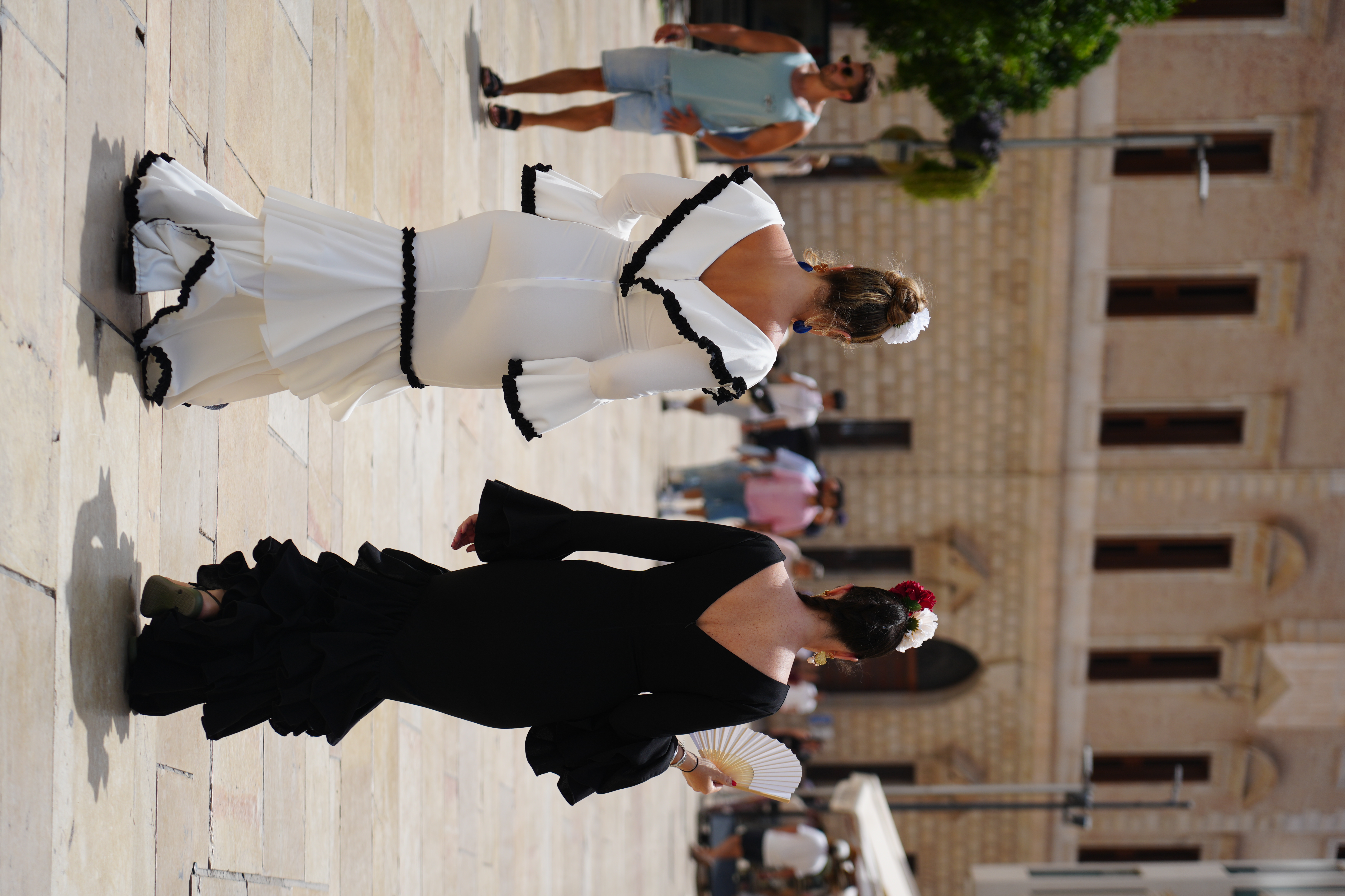 Women in flamenco feria dresses walking through central Malaga