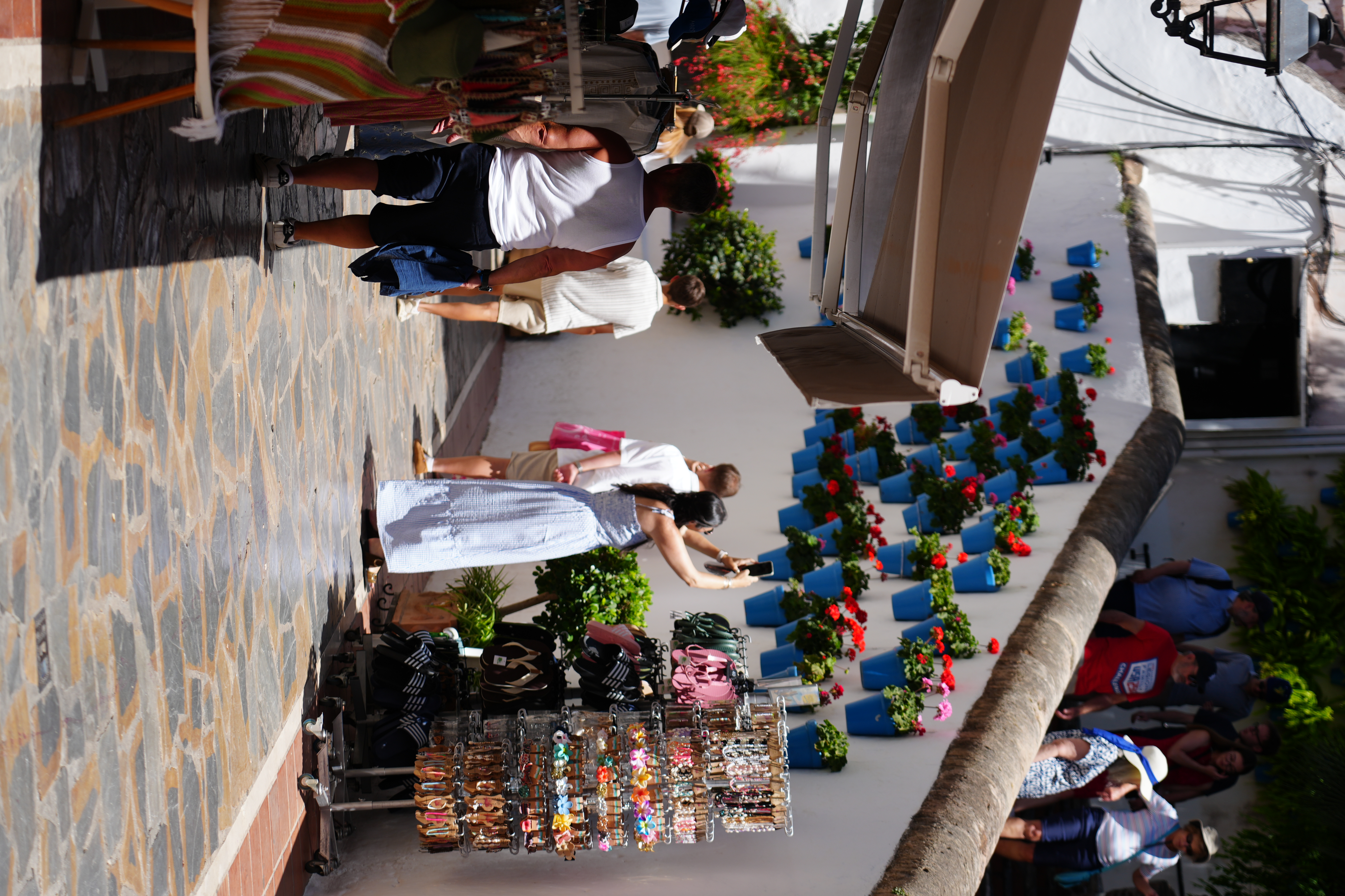 Rows of blue pots with red geraniums lining a street in Marbella