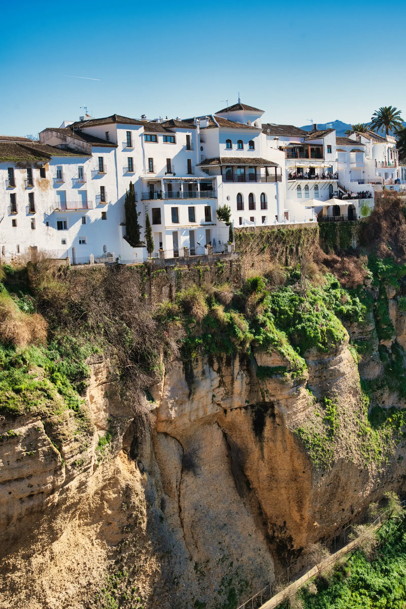 White apartment buildings perched on the sheer edge of the Ronda gorge
